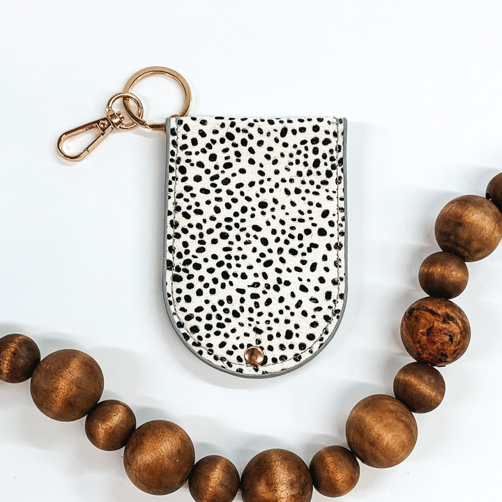 half circle snap closure hair on hide wallet that is white with black dots on a gold key ring and key clip picture on a white background