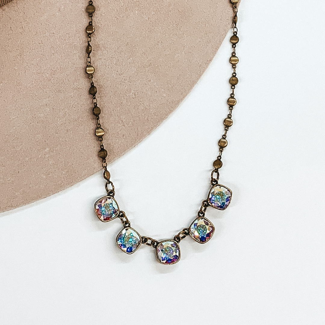 bronze chain adjustable necklace with five square ab crystals on a white and cream background