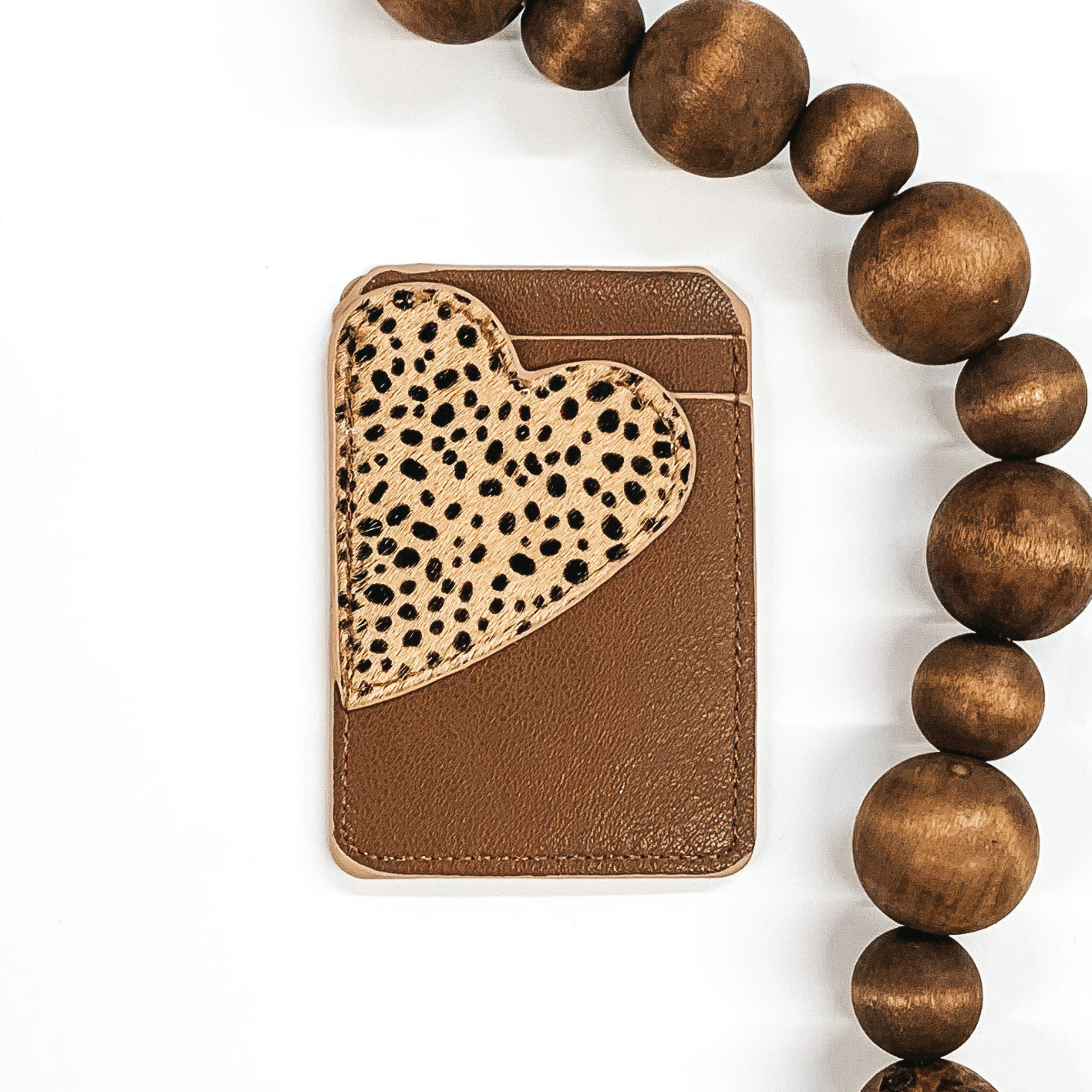 Brown card holder with two pockets that has a beige heart with a dotted print on the front and can stick to the back of phones/phone cases