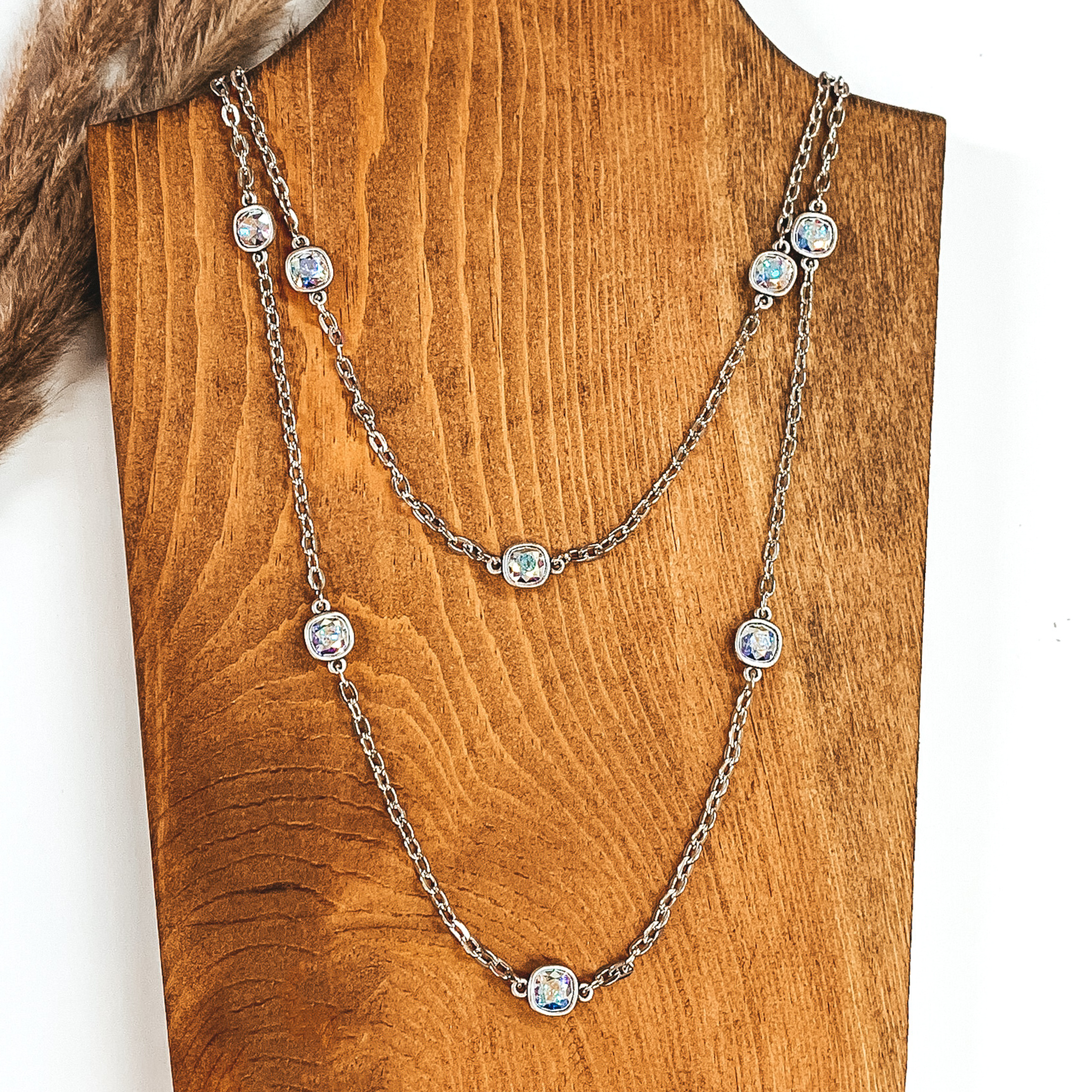 Silver chained necklace with AB square crystal spacers pictured on a white and wood background