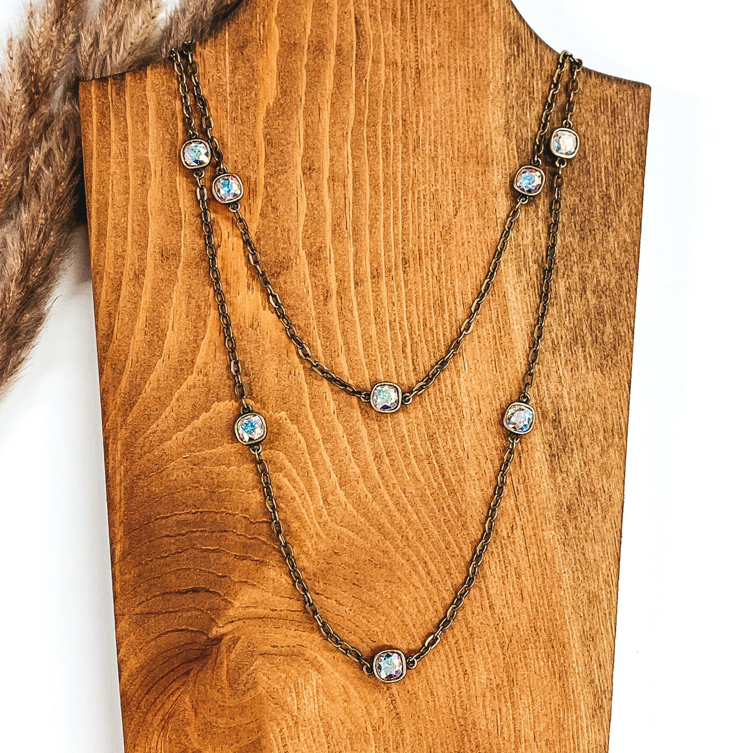 Bronze chain necklace with AB square crystal spacers pictured on a white and wood background. 