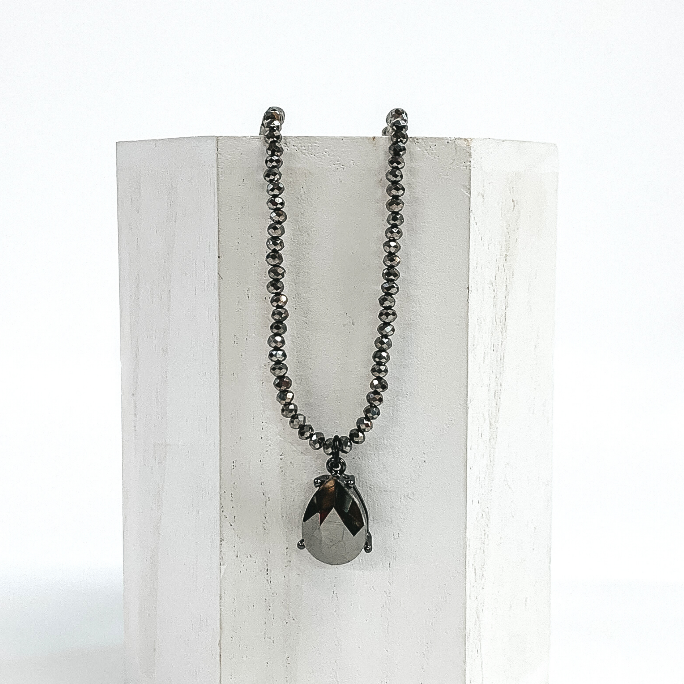 Silver crystal beaded necklace with a single teardrop crystal in jet hematite. This necklace is pictured of a white block on a white background. 