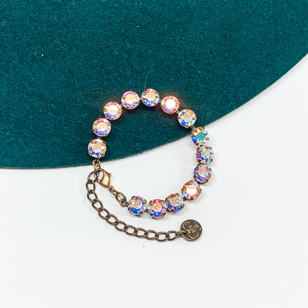 This bracelet is made up of AB crystals sitting in a bronze setting and is adjustable. This bracelet is pictured on a green and white background. 