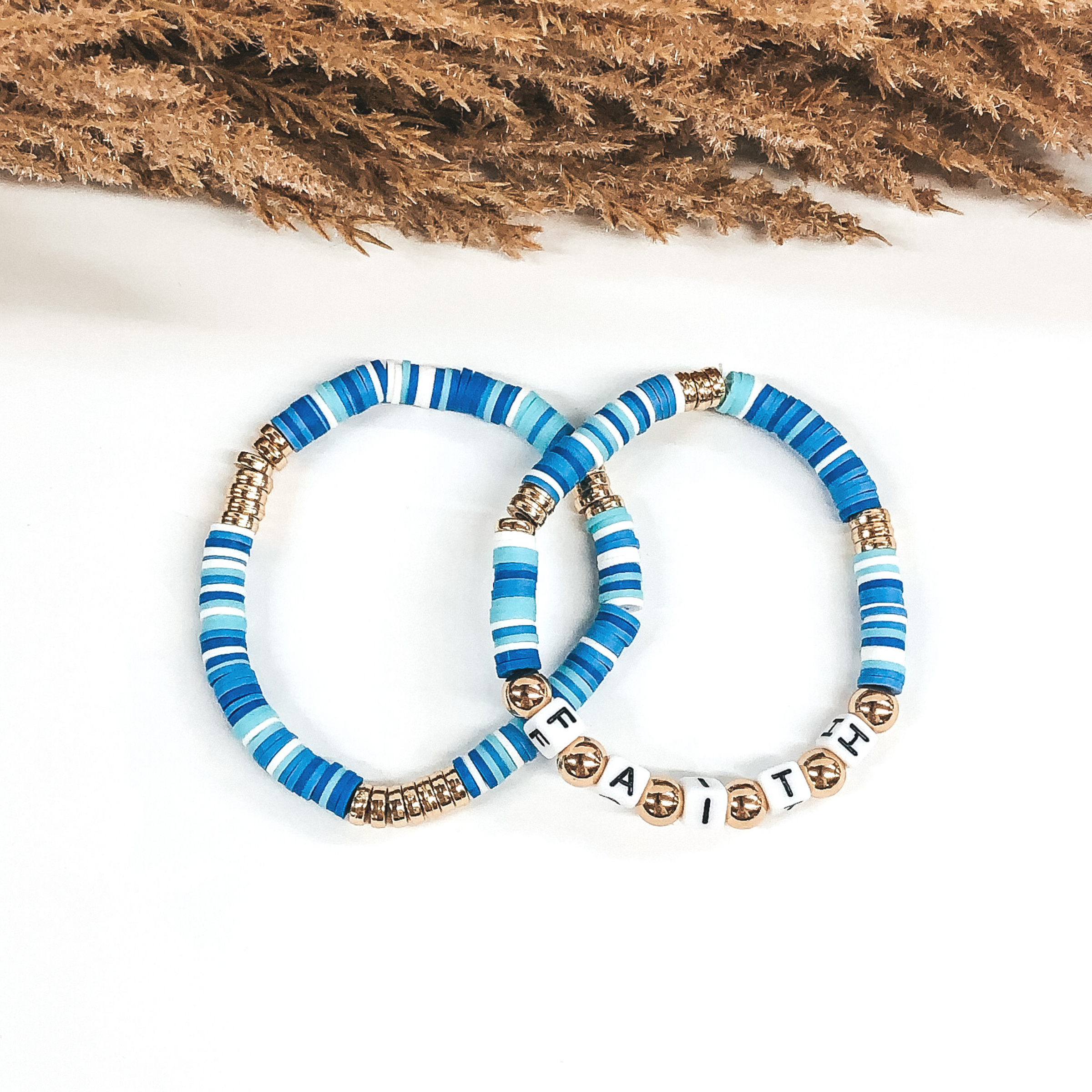 Two bracelets that has a mix of blue colors and white disk beads. On one bracelet, you have three sections of gold disc beads. On the other bracelet you have three smaller section of gold disc beads and then letter beads that spell out "FAITH" with gold spacers in between. These bracelets are pictured on a white background. 