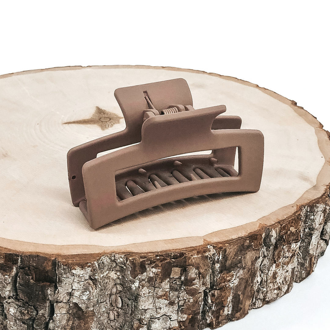 Matte taupe rectangle claw clip with rectangle cutout. This clip is pictured on a piece of wood on a white background.