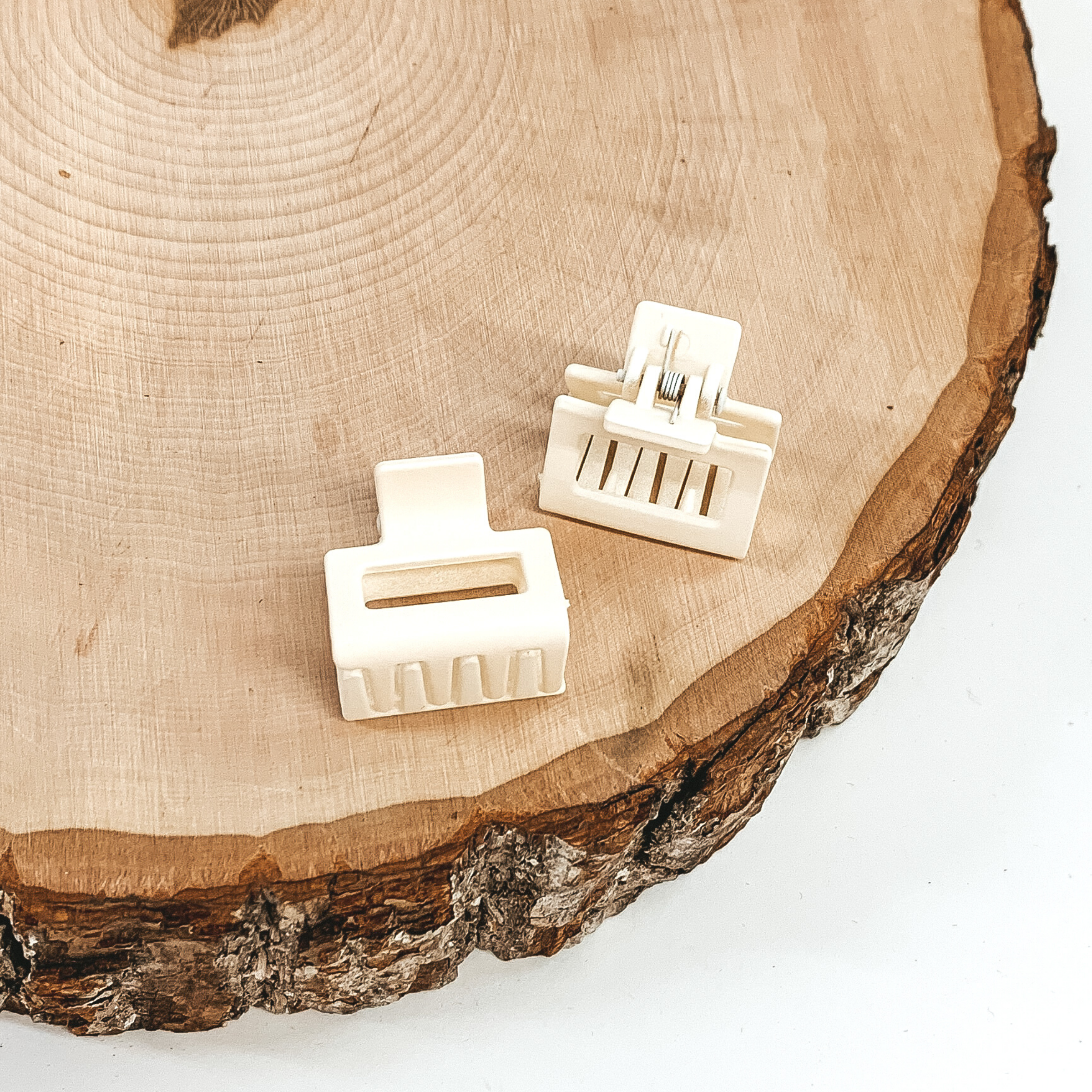 Matte ivory rectangle claw clips with a rectangle cutout. This clip is pictured on a piece of wood on a white background.