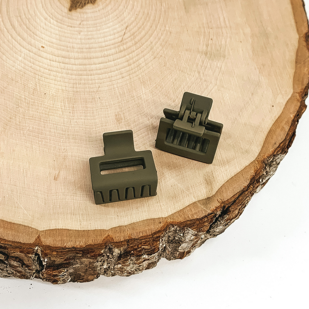Matte olive green rectangle claw clips with a rectangle cutout. This clip is pictured on a piece of wood on a white background.