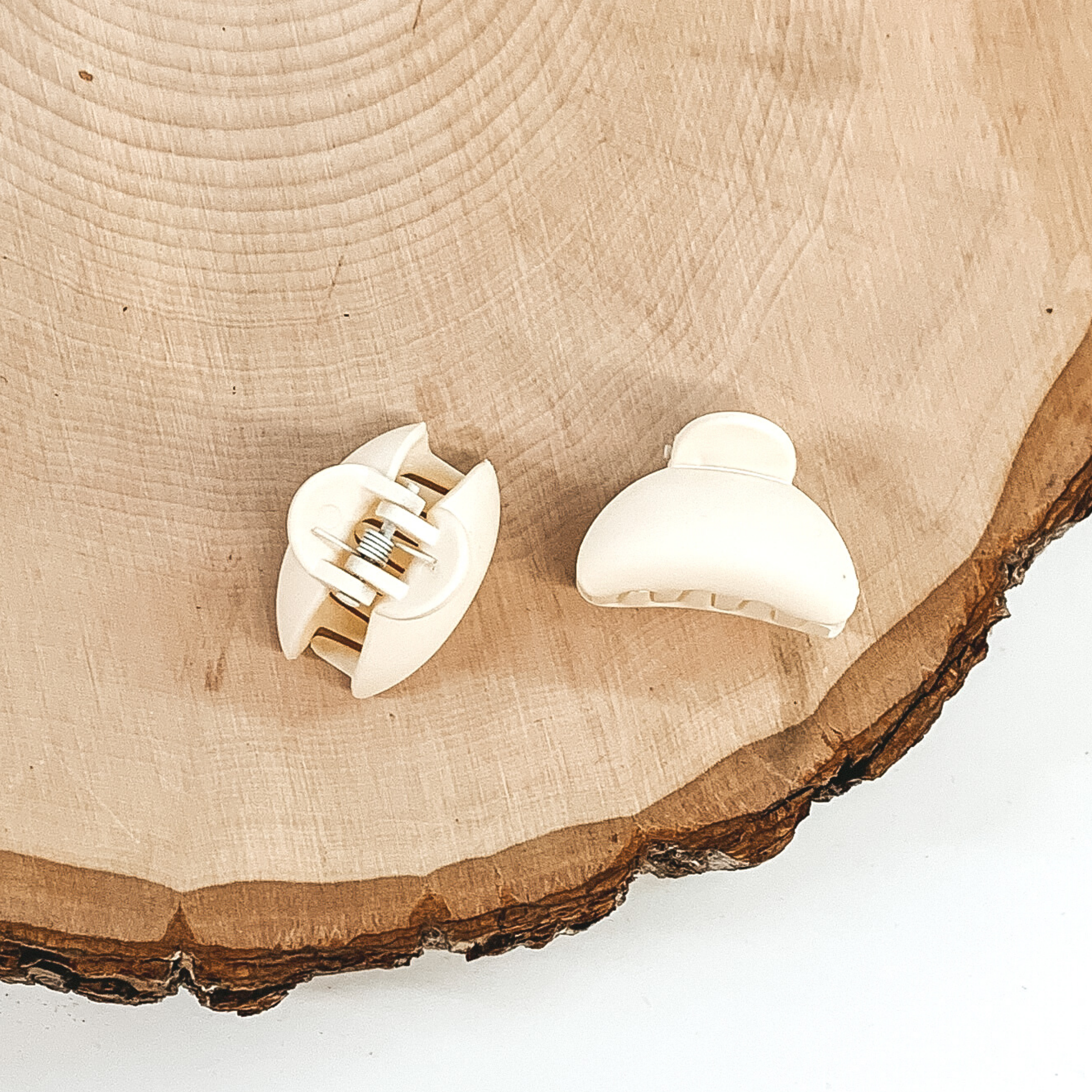 Matte ivory oval claw clips with an oval cutout. This clip is pictured on a piece of wood on a white background.