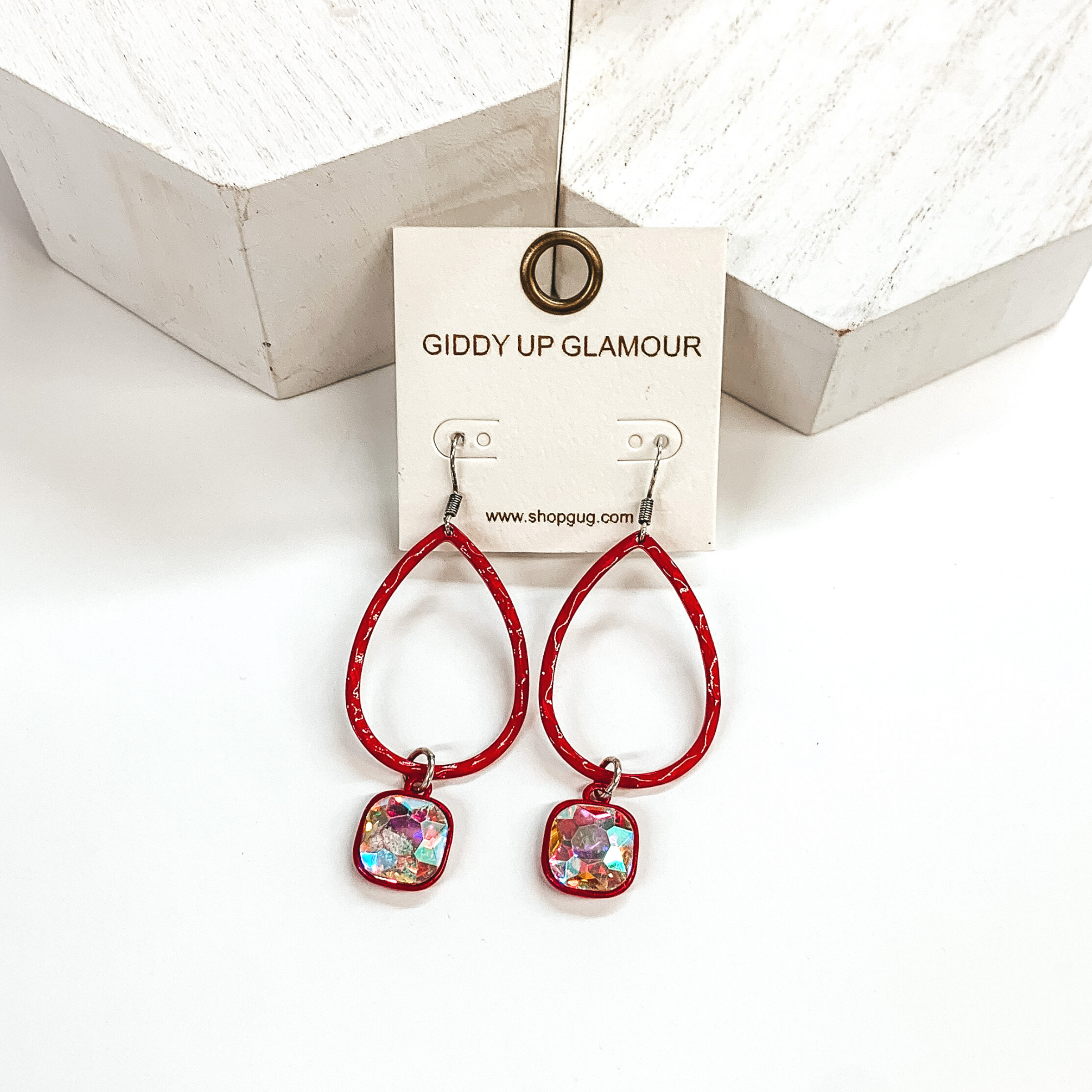 Red teardrop hammered earrings with a hanging cushion cut ab crystal. These earrings are pictured on a white background with white blocks at the top of the picture.