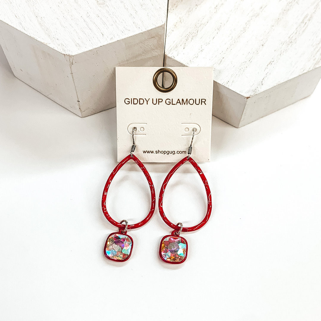 Red teardrop hammered earrings with a hanging cushion cut ab crystal. These earrings are pictured on a white background with white blocks at the top of the picture.