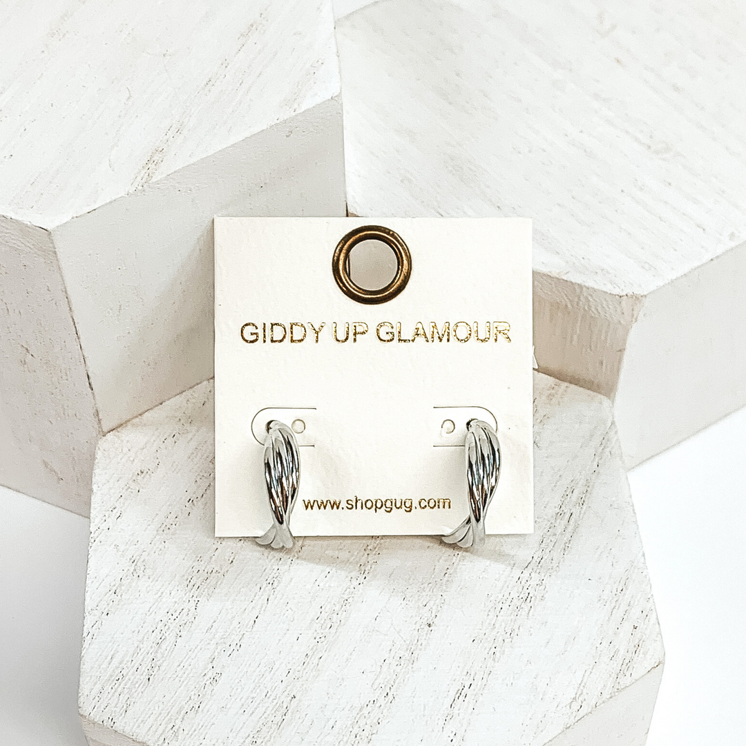Silver twisted hoops with three layers. These earrings are pictured on a white earrings holder laying on white blocks