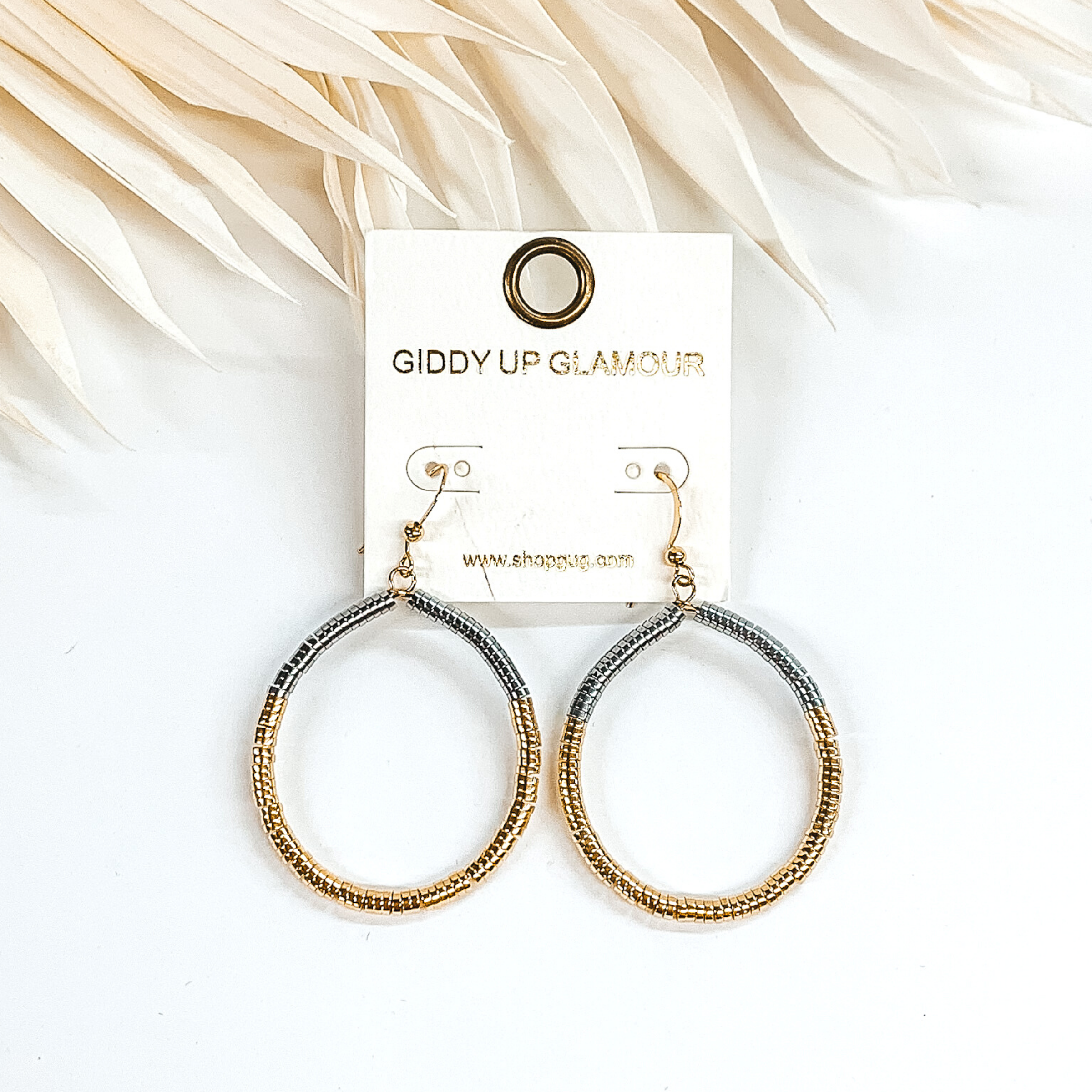 Circle drop disk beaded earrings in gold and silver. These earrings are pictured on a white background with ivory leaves at the top of the picture.