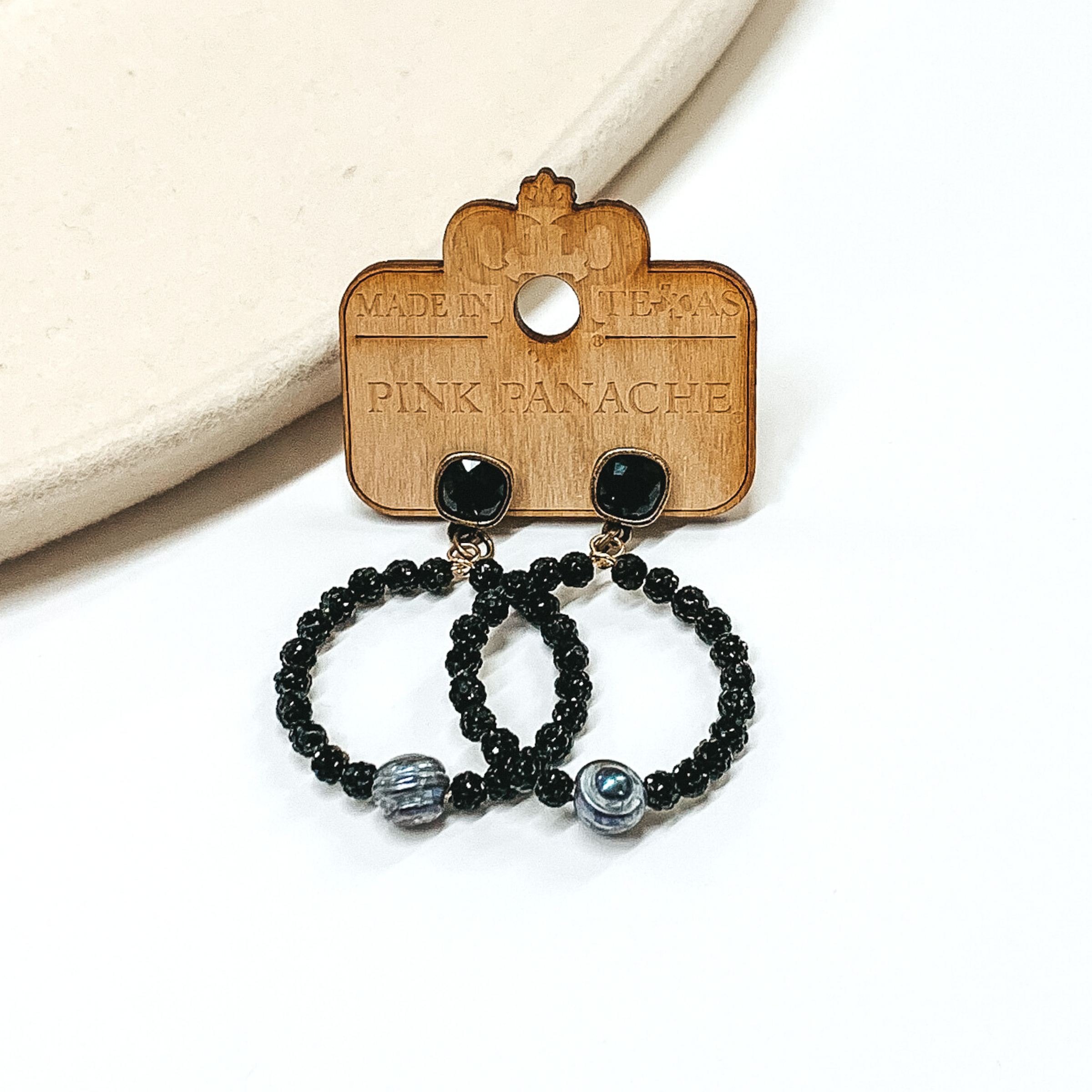 Black cushion cut crystal studs with hanging circle pendant. The circle pendant is covered in black crystal beads  with a black pearl bead at the bottom. 