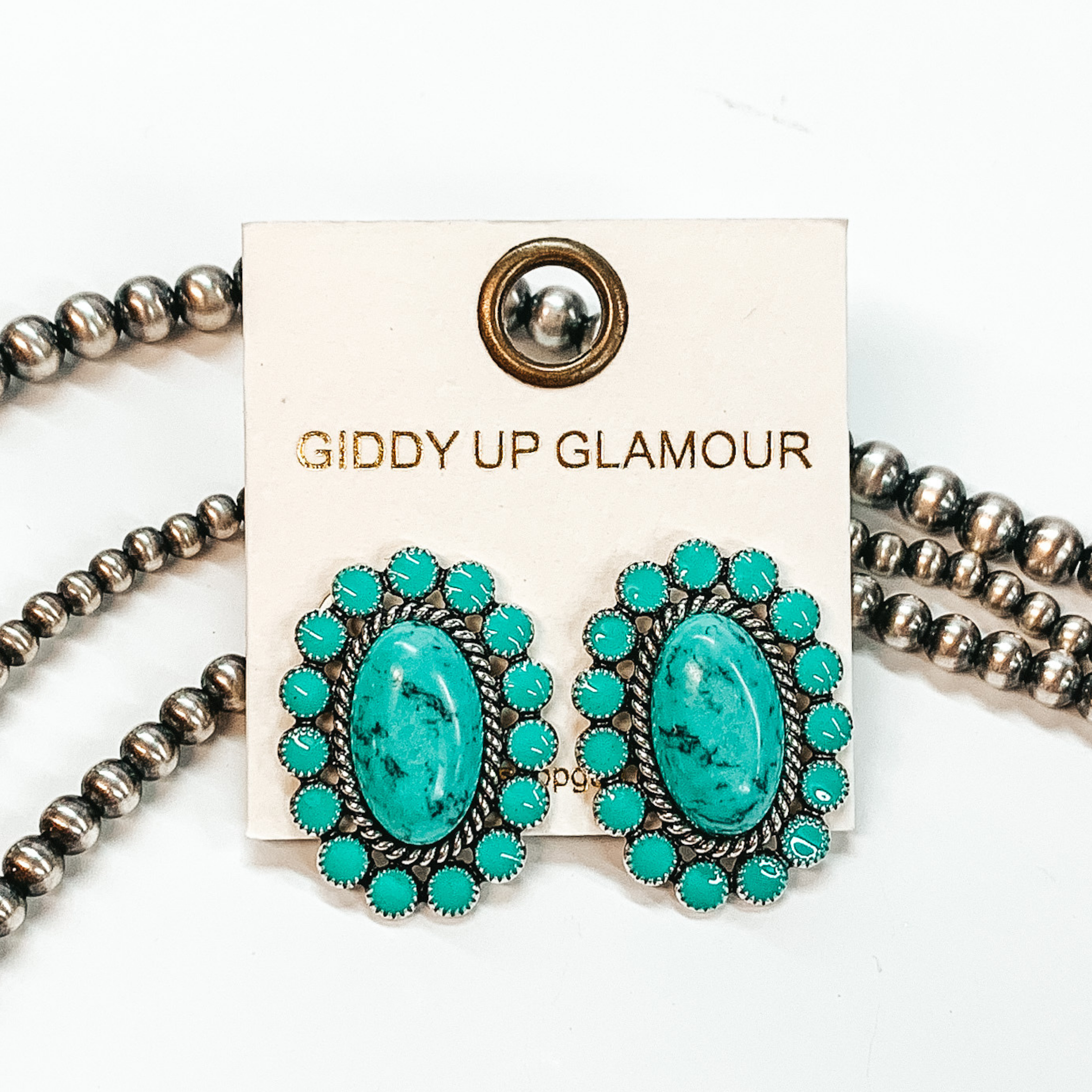 Turquoise concho earrings outlined by  silver detailing and turquoise circles around.  Pictured in a white background with beads as decor.