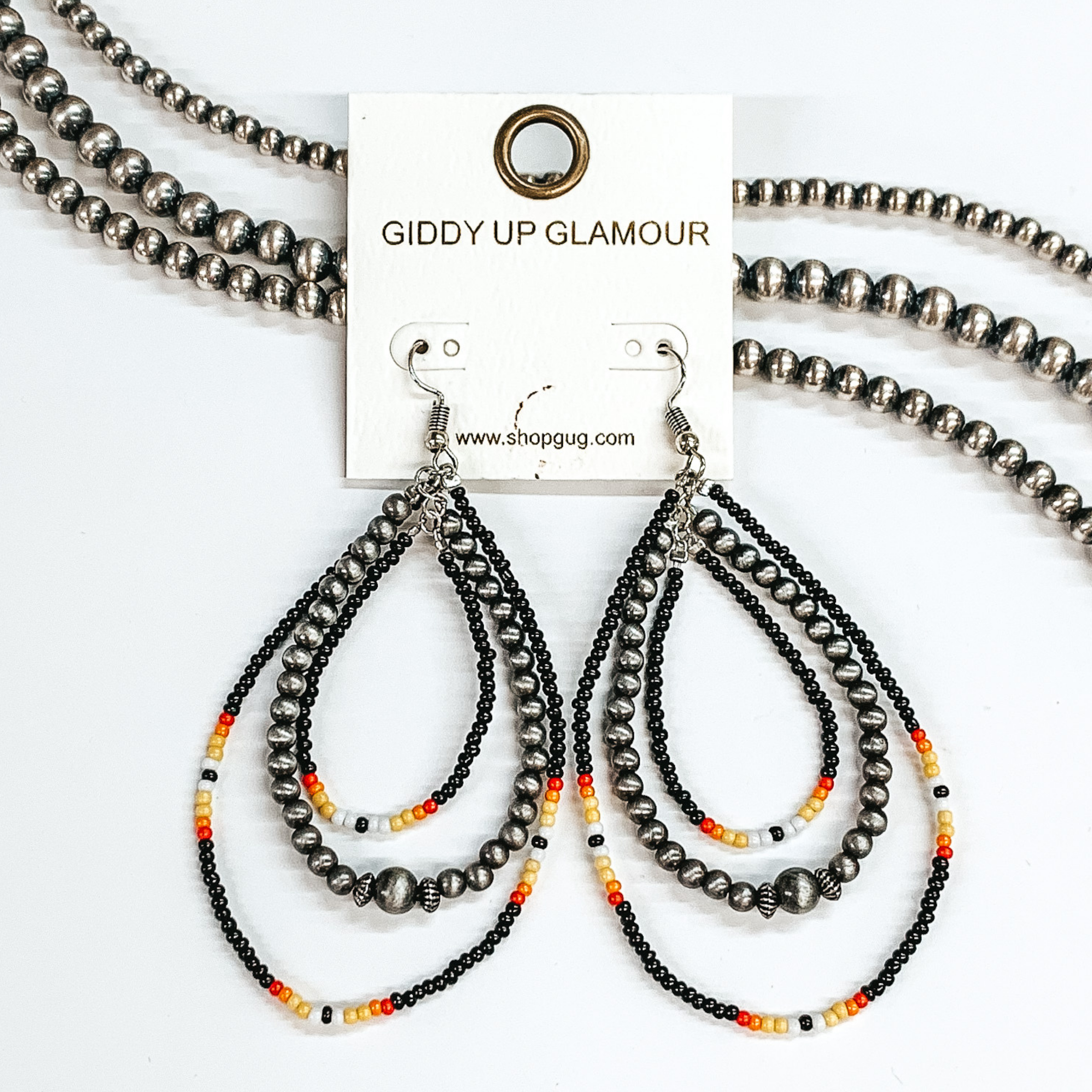 Three layer, hanging beaded teardrop earrings. The majority of the beads are black with three  segments including maroon, red, yellow, white,  and black beads. Second layer has faux Navajo  beads with one large bead in the center.  These earrings are pictured on a white background  with beads as decor.