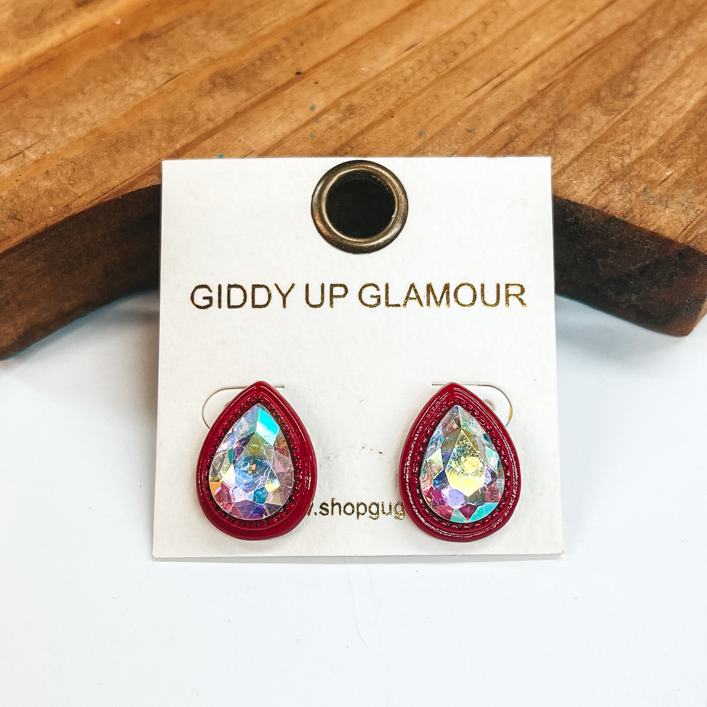 Red teardrop post back earrings with an AB crystal  in the center. These earrings  are pictured on a white background with a brown block in the back.