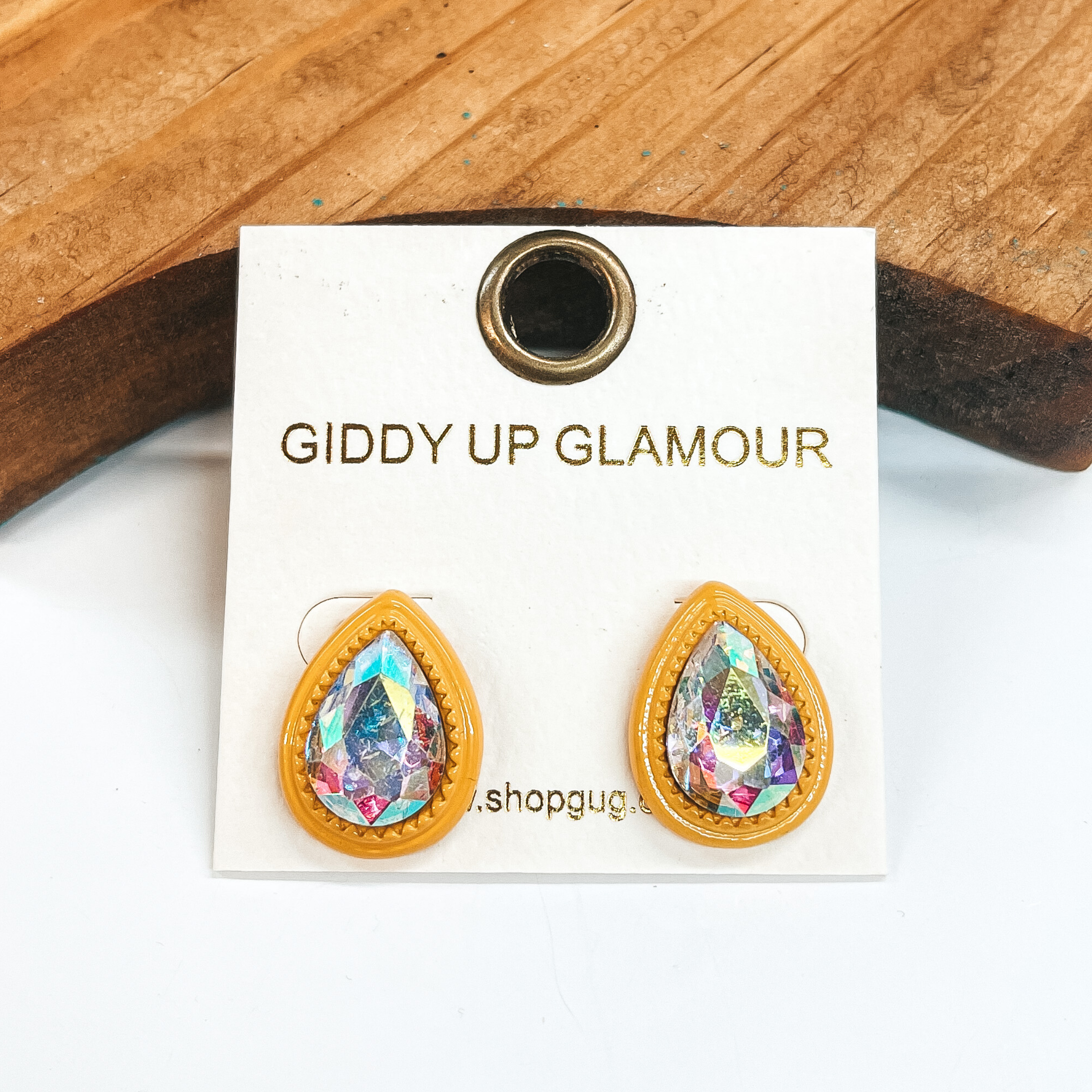 Yellow teardrop post back earrings with an AB crystal  in the center. These earrings  are pictured on a white background with a brown block in the back.