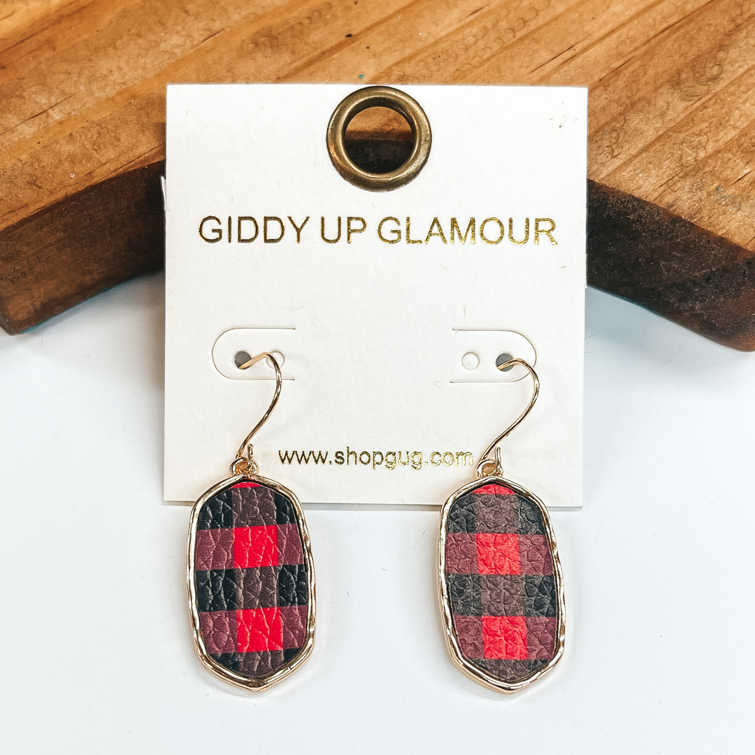 Rectangular earrings with gold setting in  red and black plaid. Taken in a white background  with a brown block in the back.