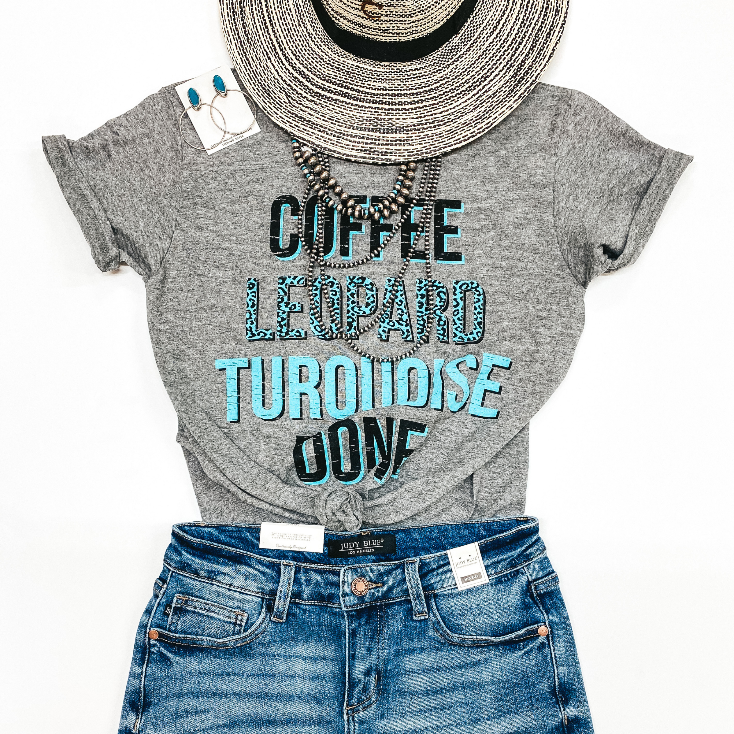 A grey graphic tee that says "Coffee Leopard Turquoise Done". Pictured with denim shorts, genuine Navajo jewelry, and a straw hat.