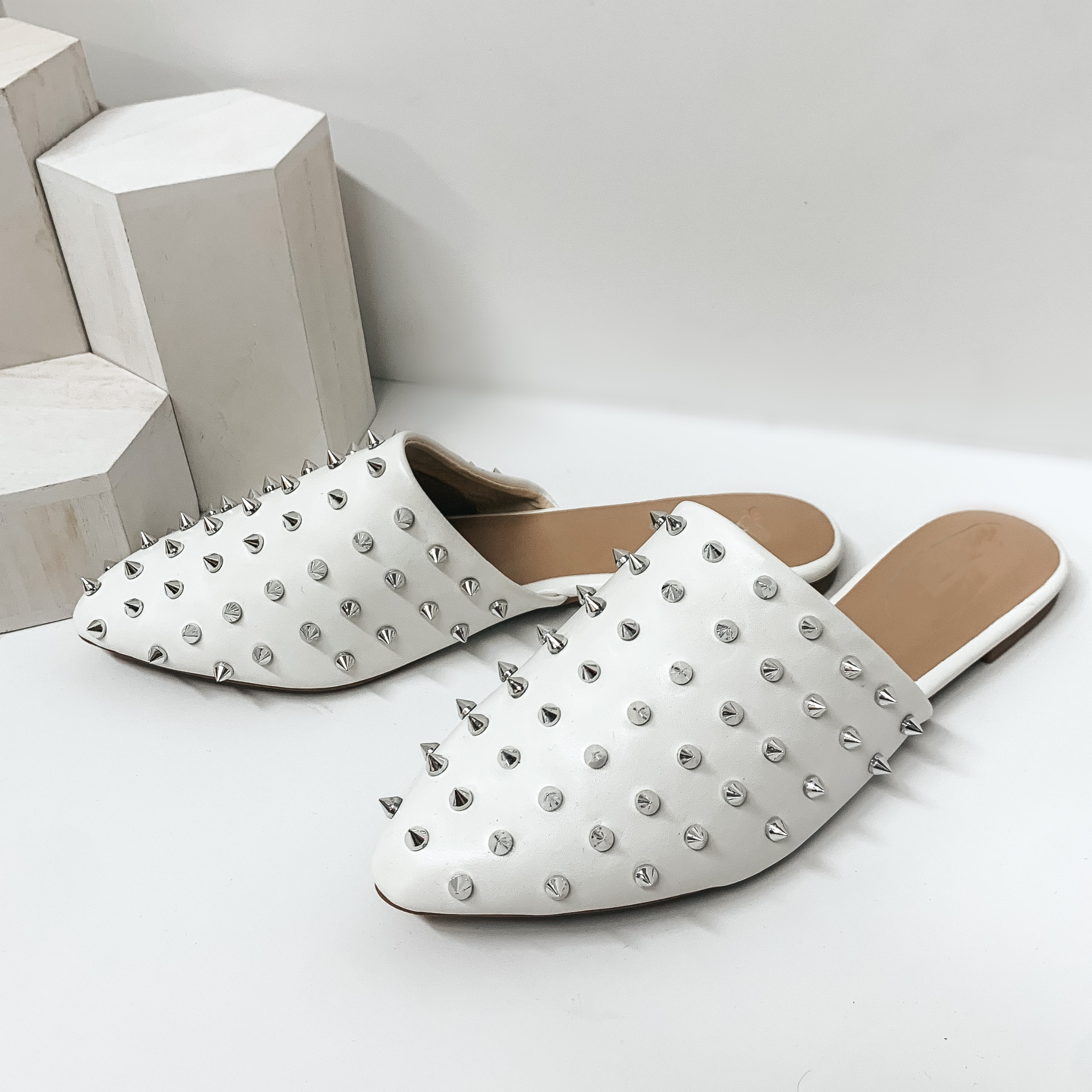 Uptown Girl Silver Spiked Slide On Mules in White. These cute shoes will give you an uptown flare! They include a silver spike embellished upper, a pointed toe, and a 0.25 inch high heel. Pair these shoes with any outfit for a fun look!