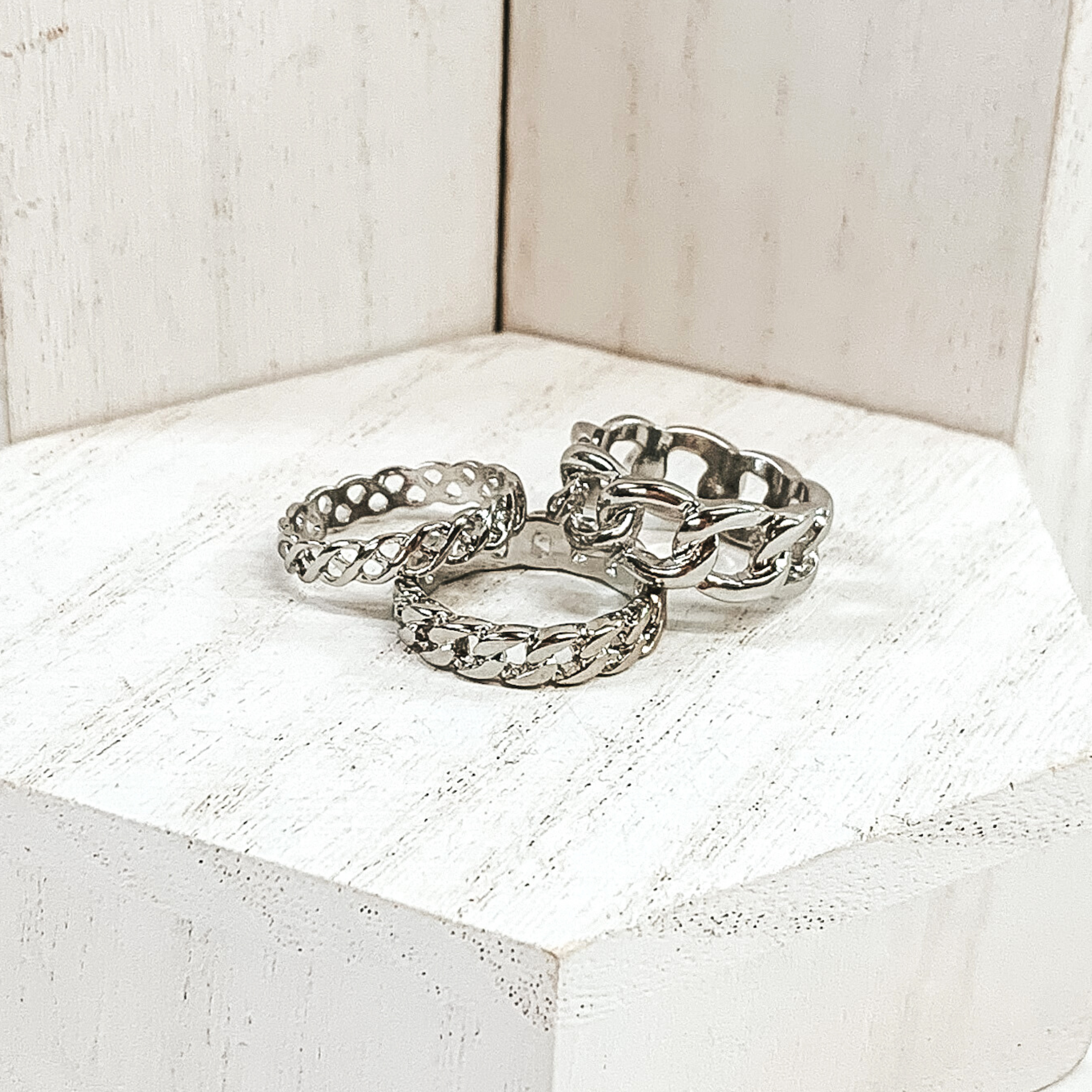 This set of silver rings include three different band widths and different types of chains for each ring. These rings are pictured on a white background.