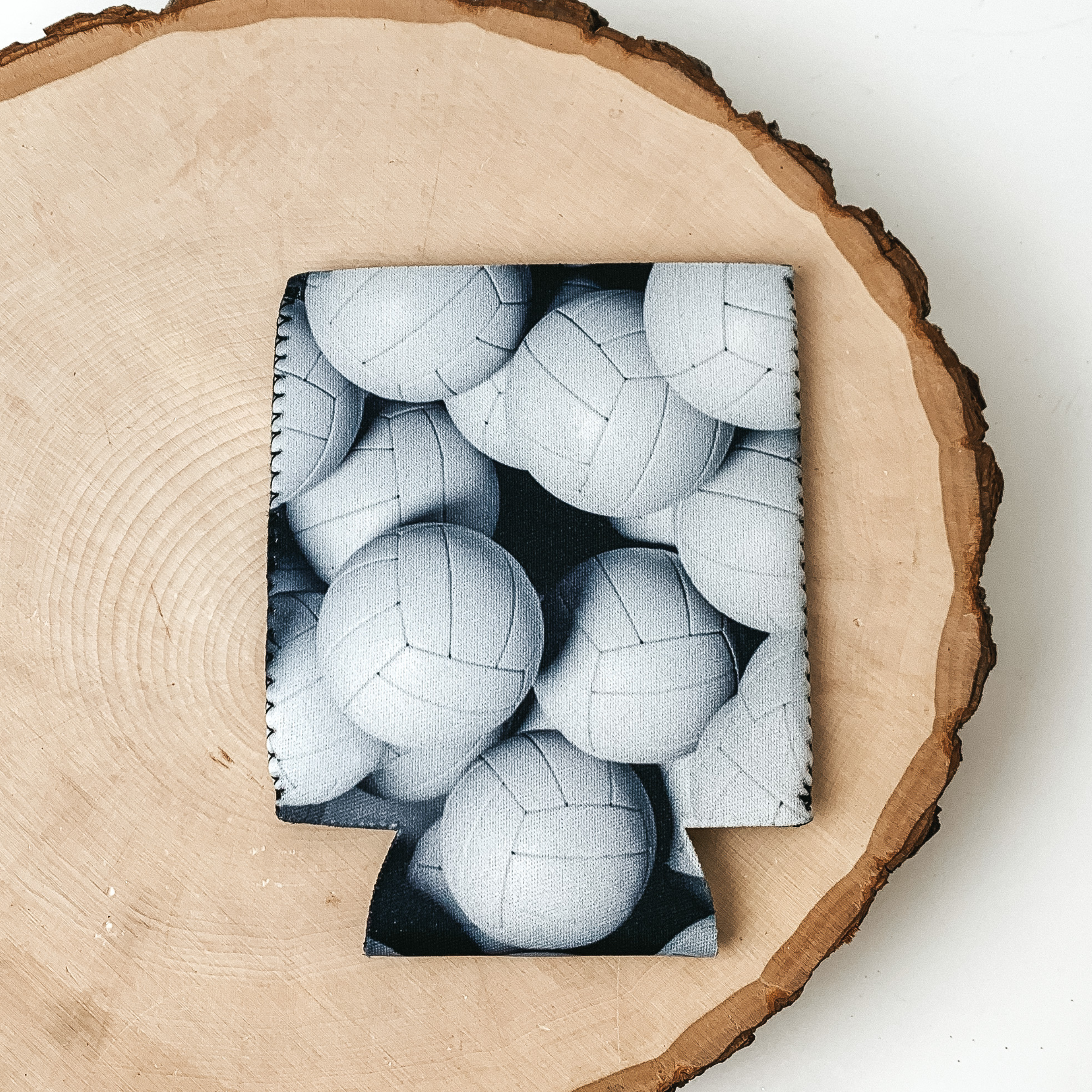 This Volleyball print kooozie is pictured on a peice of wood, with a white background. 