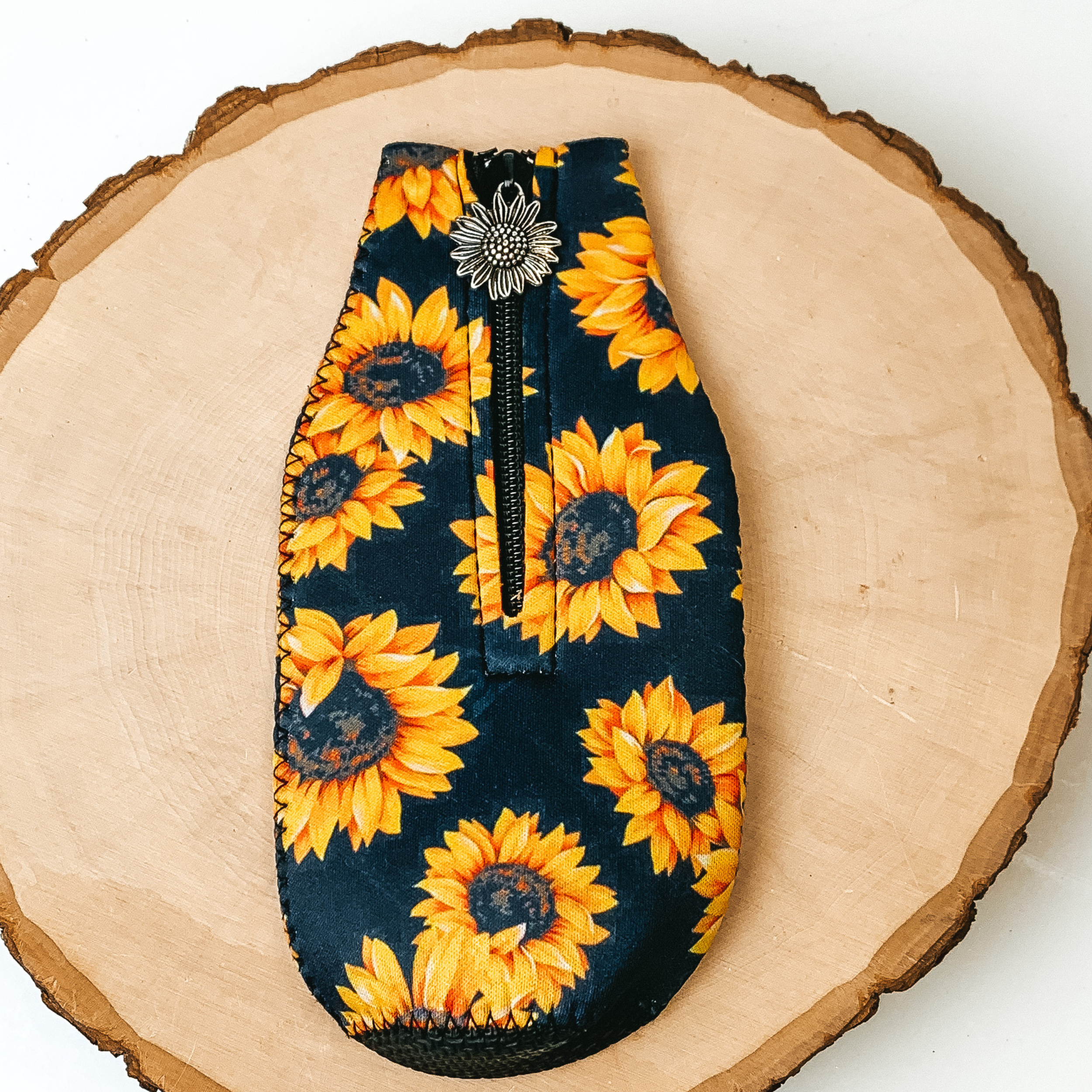 This Sunflower Print Zip Up kooozie With Sunflower Charm is pictured on a peice of wood, with a white background.  