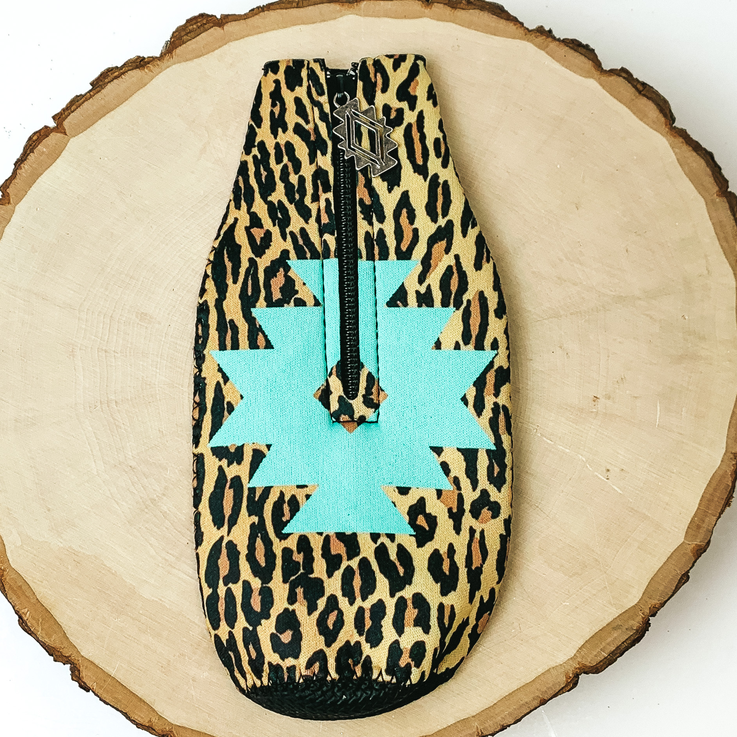 This Navajo and Leopard Print Zip Up koozie With Navajo Charm is pictured on a peice of wood, with a white background.  