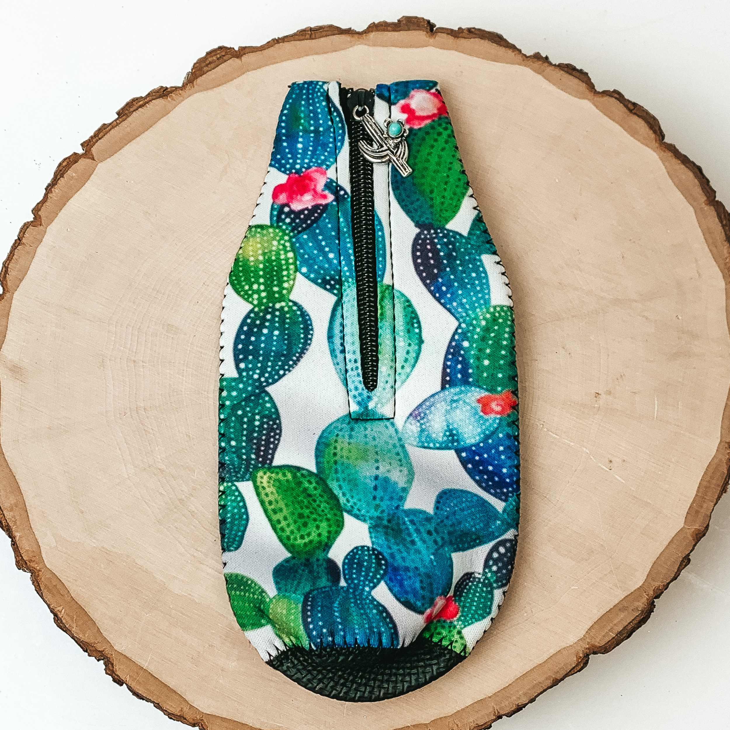 This Watercolor Cactup Zip Up Koozie with Cactus Charm is pictured on a peice of wood, with a white background. 