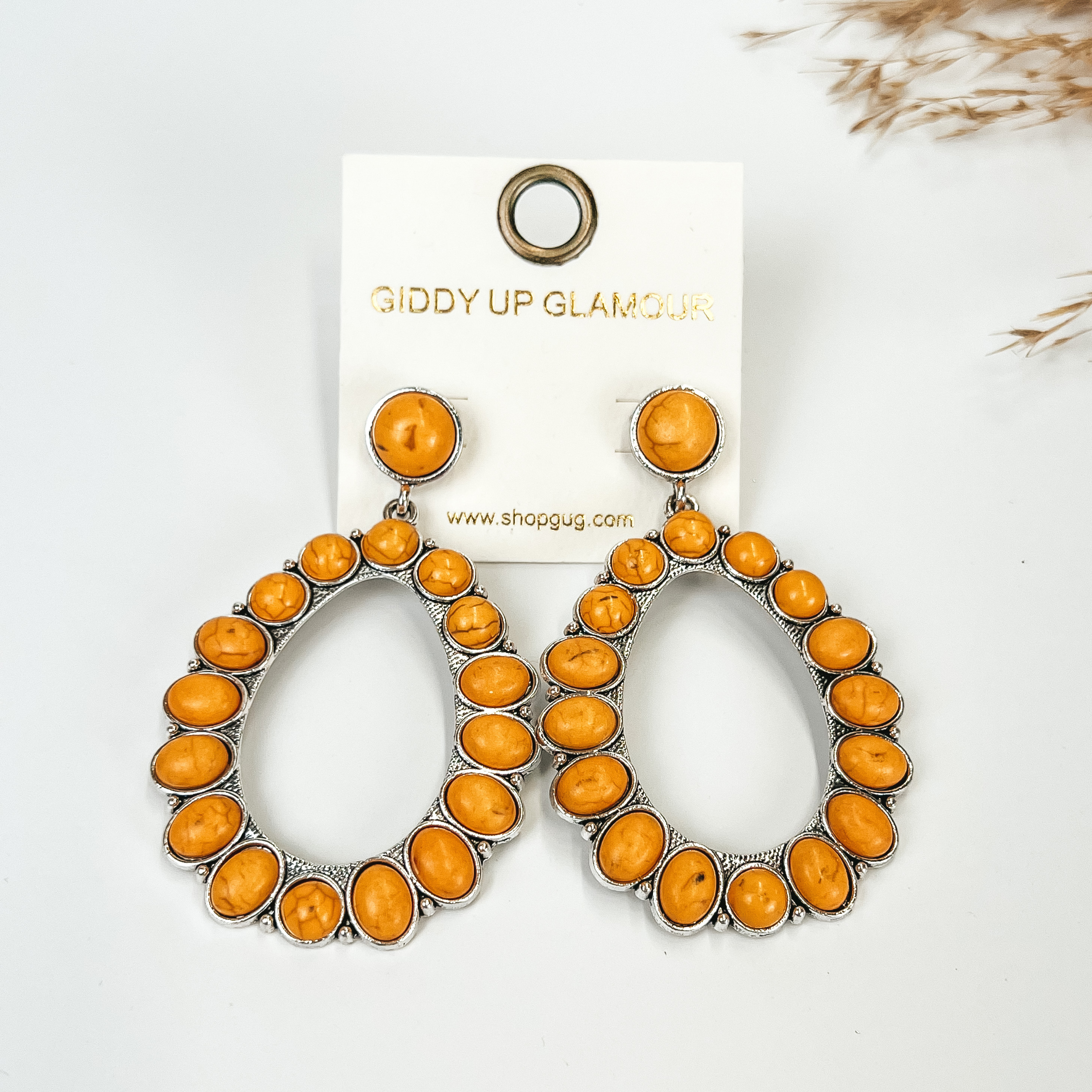 Mustard Yellow stoned teardrop earrings, with pompous grass in the top right hand corner, on a white background.