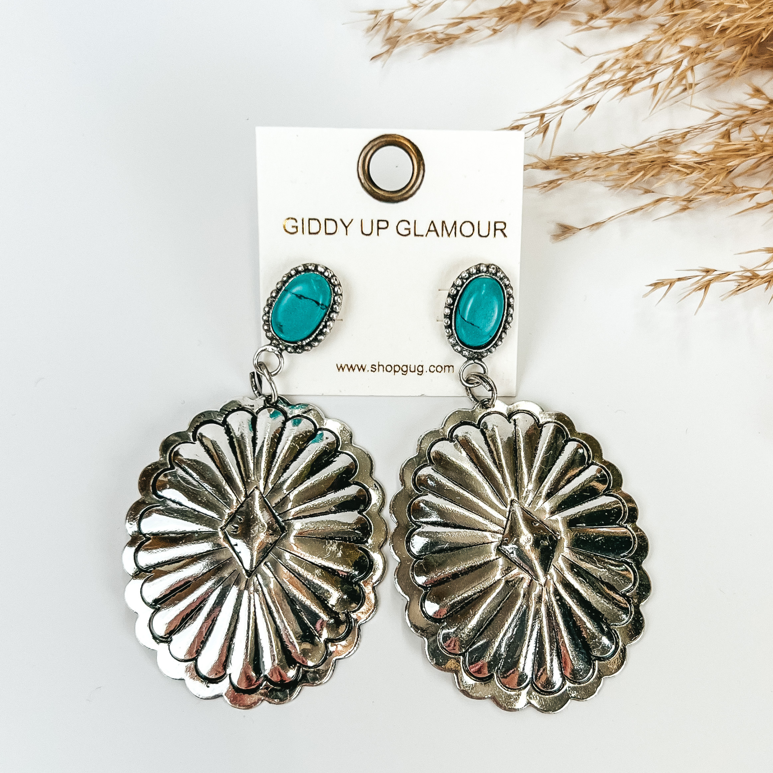 Turquoise Post Earrings with Silver Pendant, with pompous grass in the top right hand corner, on a white background. 
