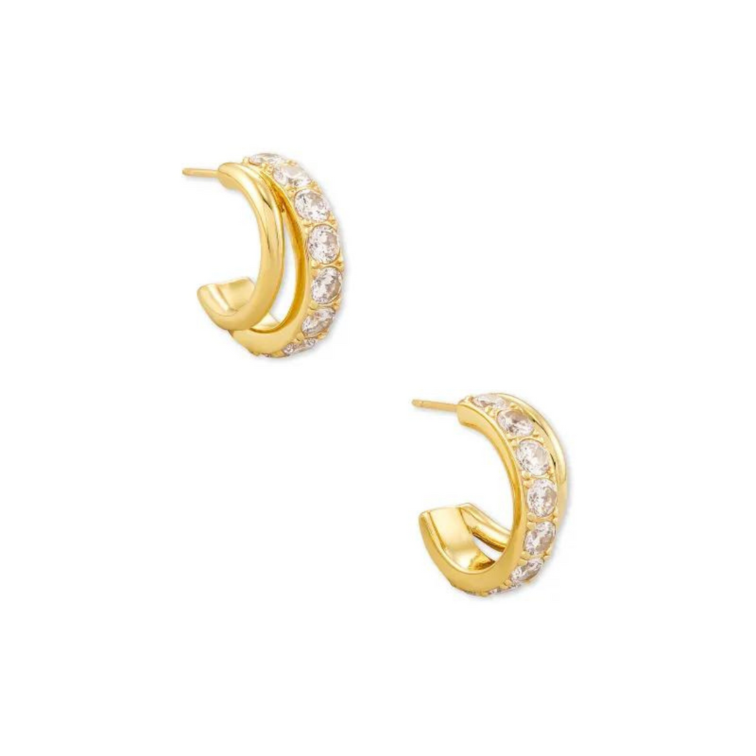 Gold huggie hoop earrings with white crystals pictured on a white background.