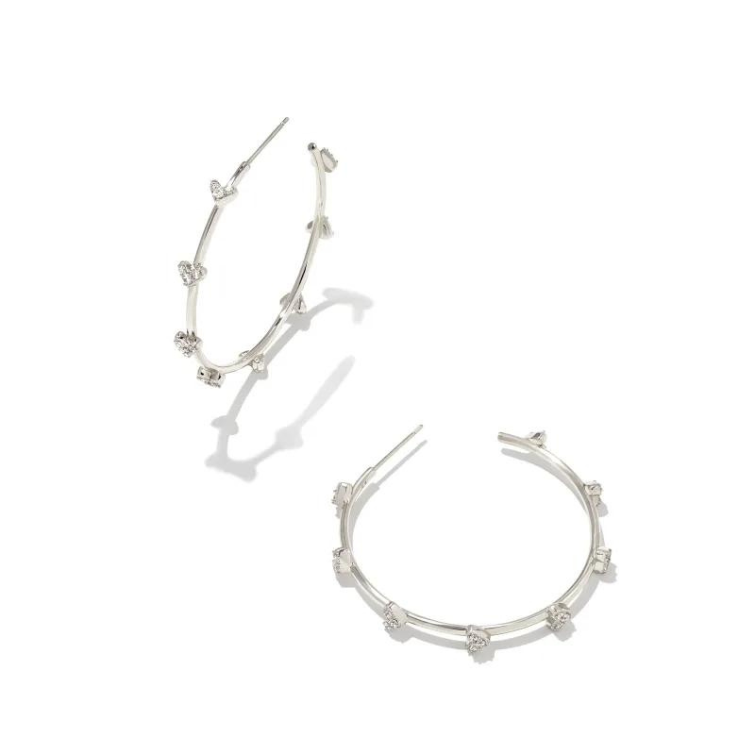 Silver hoop heart earrings with white crystals pictured on a white background.