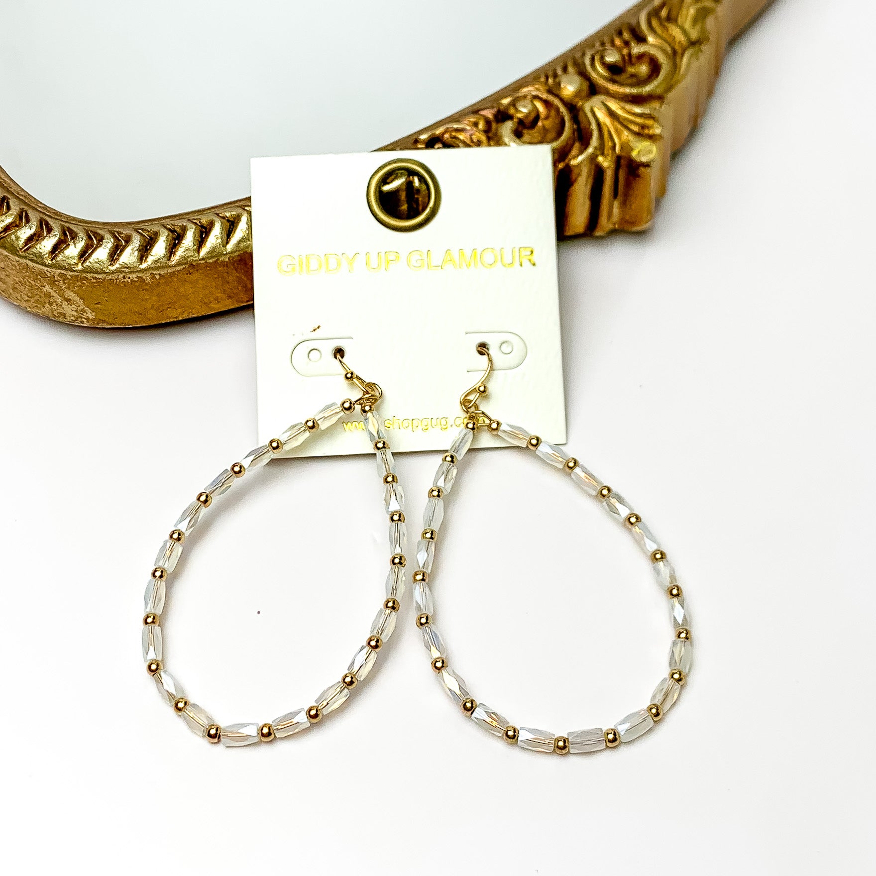 AB Beaded open drop earrings with gold tone features. Pictured on a white background with a gold frame through it.