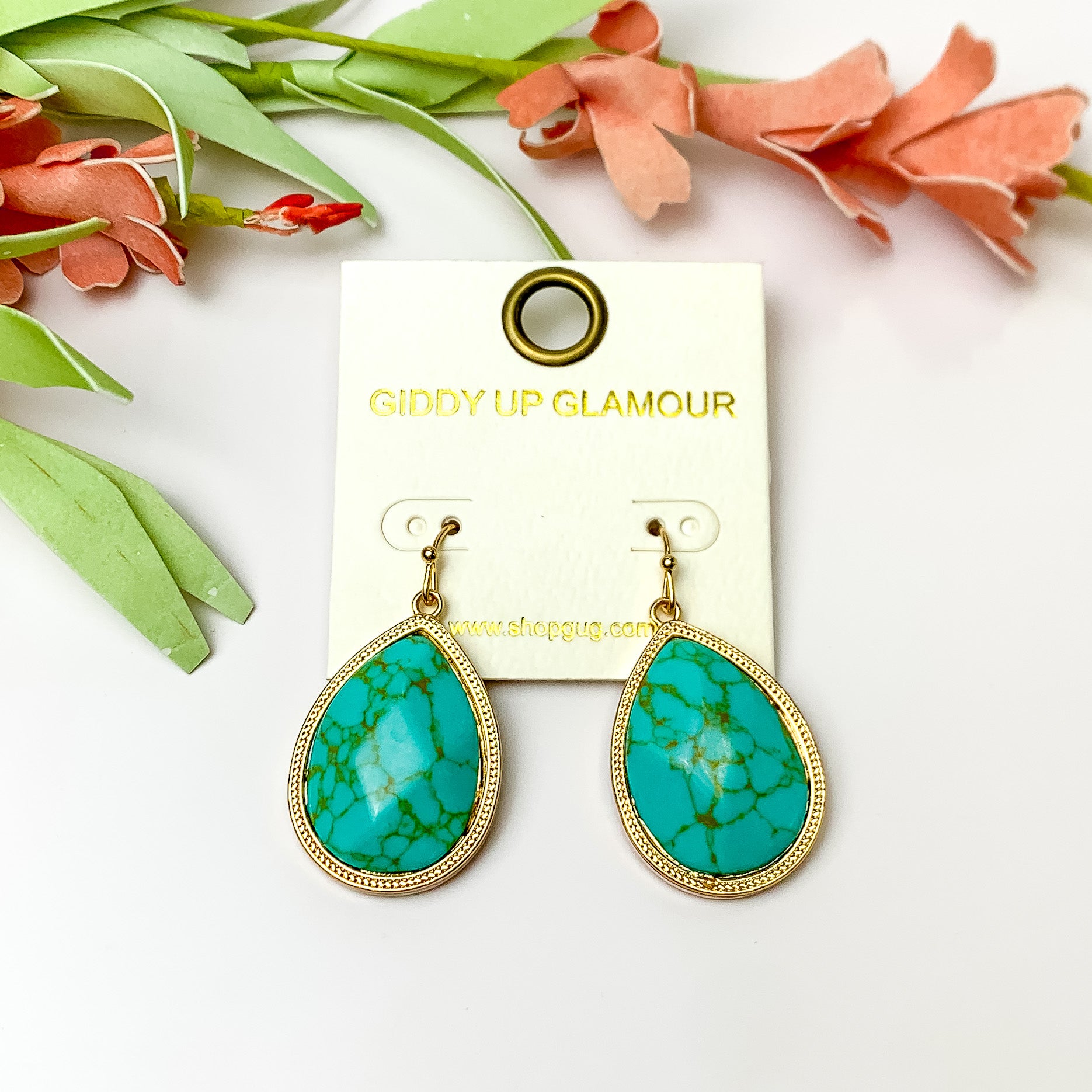 Turquoise Drop Earrings with Gold tone outline. Pictured on a white background with flowers at the top.