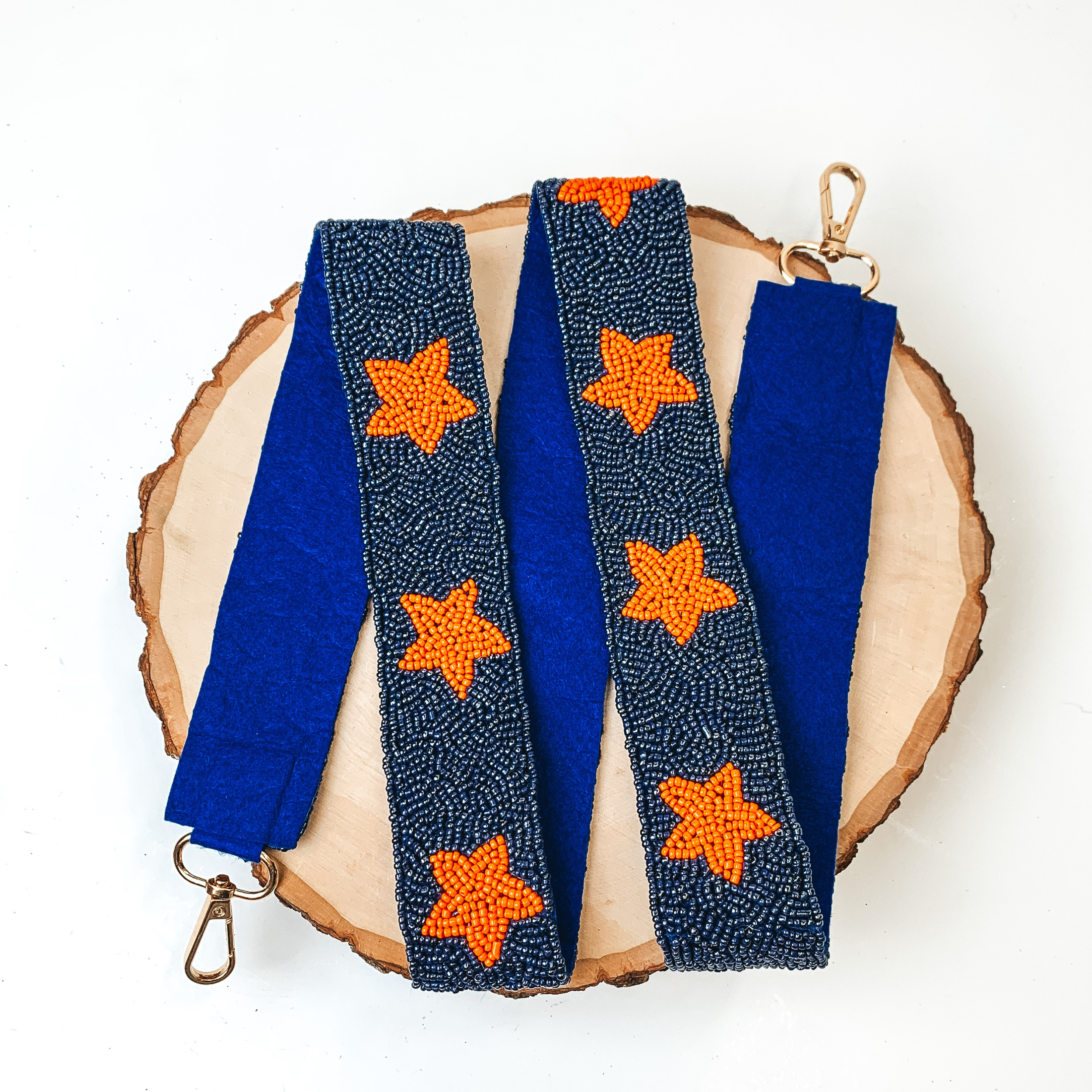 Beaded Orange Stars Purse Strap in Navy Blue, pictured on a piece of wood, with a white background. 