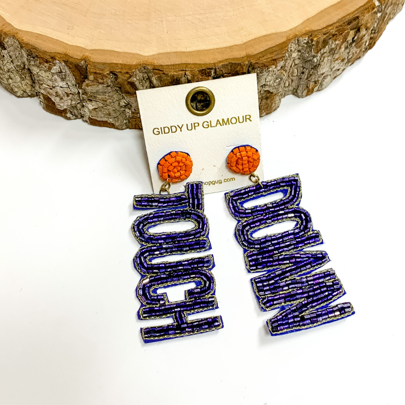 Orange circle post back earrings. These earrings include the words "Touch" and "Down" in navy beads. These earrings are pictured propped up on a circle piece of wood.