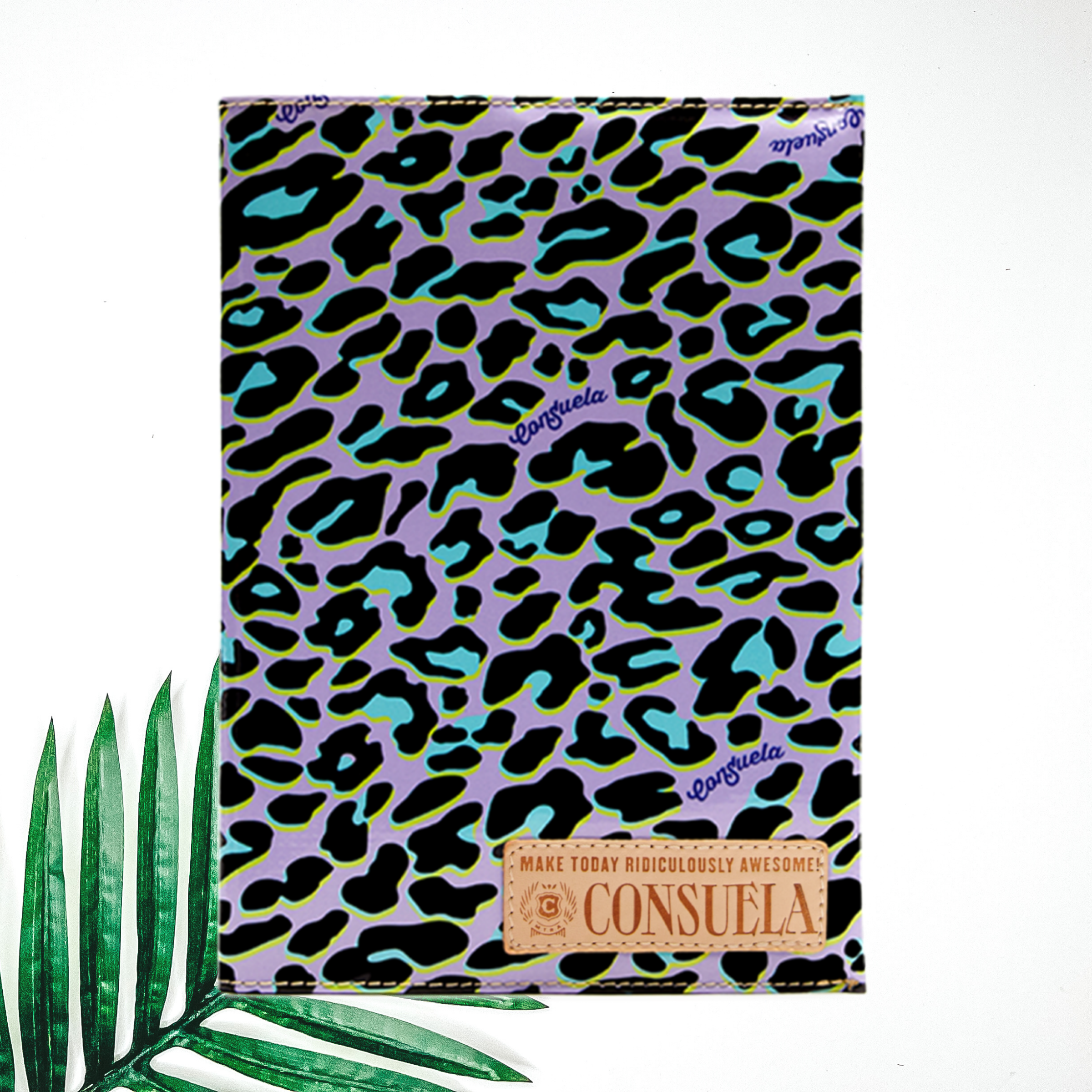 Centered in the picture is a notebook in purple cheetah. To the right of the notebook is a palm leaf, all on a white background.