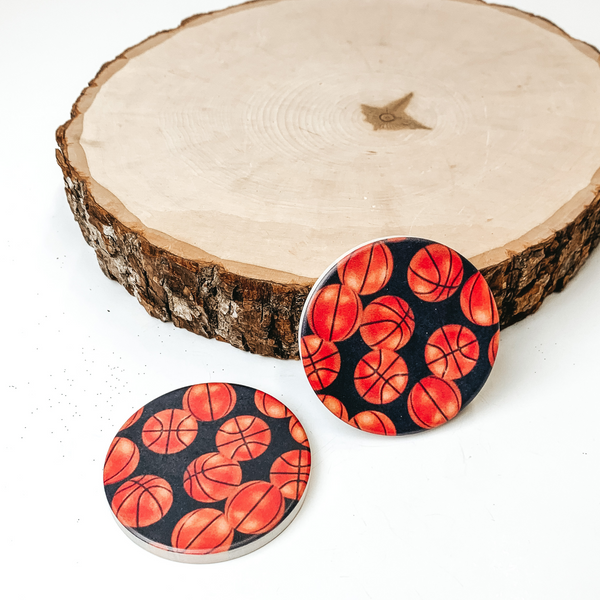 Set of two Basketball car coasters pictured on a piece of wood, with a white background. 