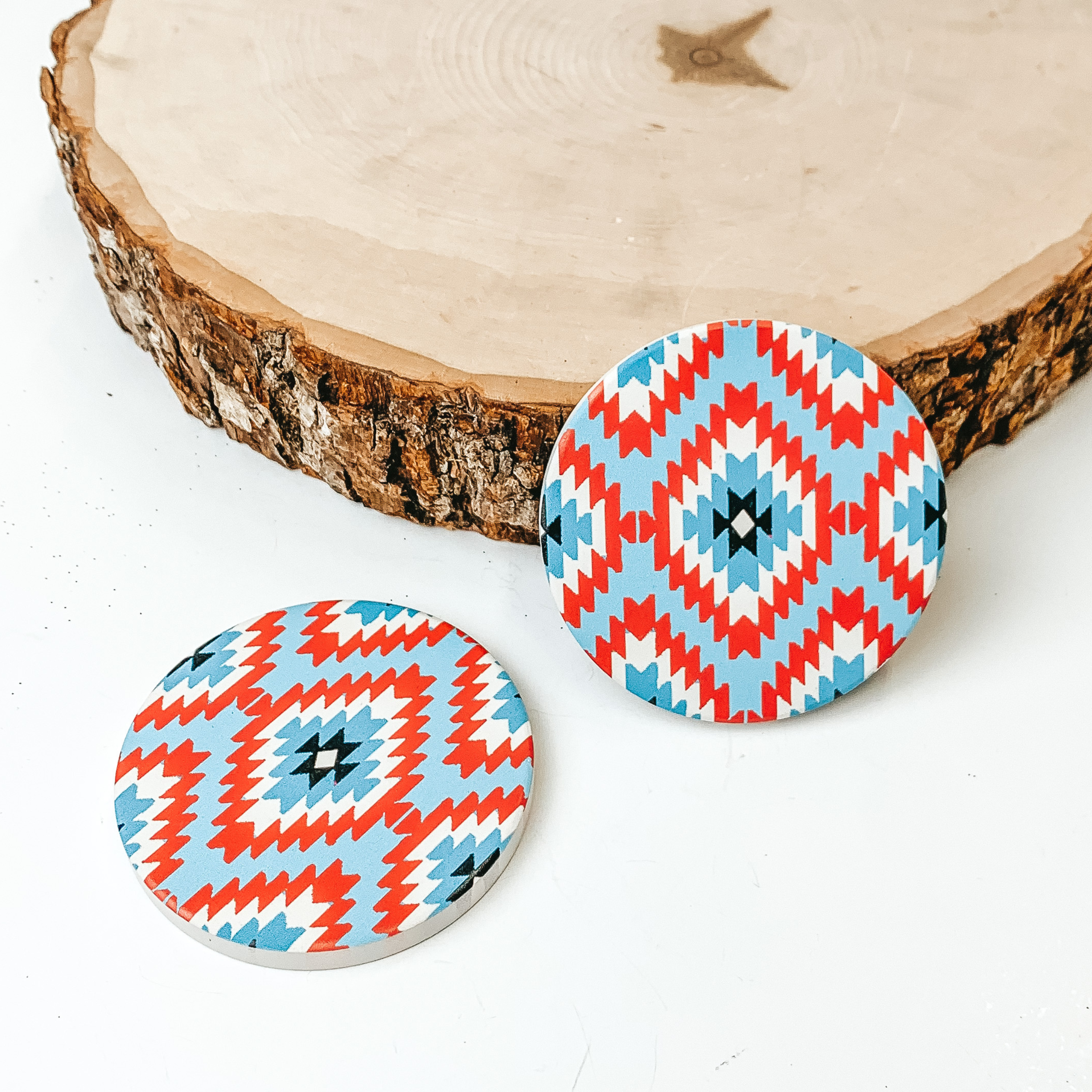 Set of two Tribal Print car coasters pictured on a piece of wood, with a white background. 