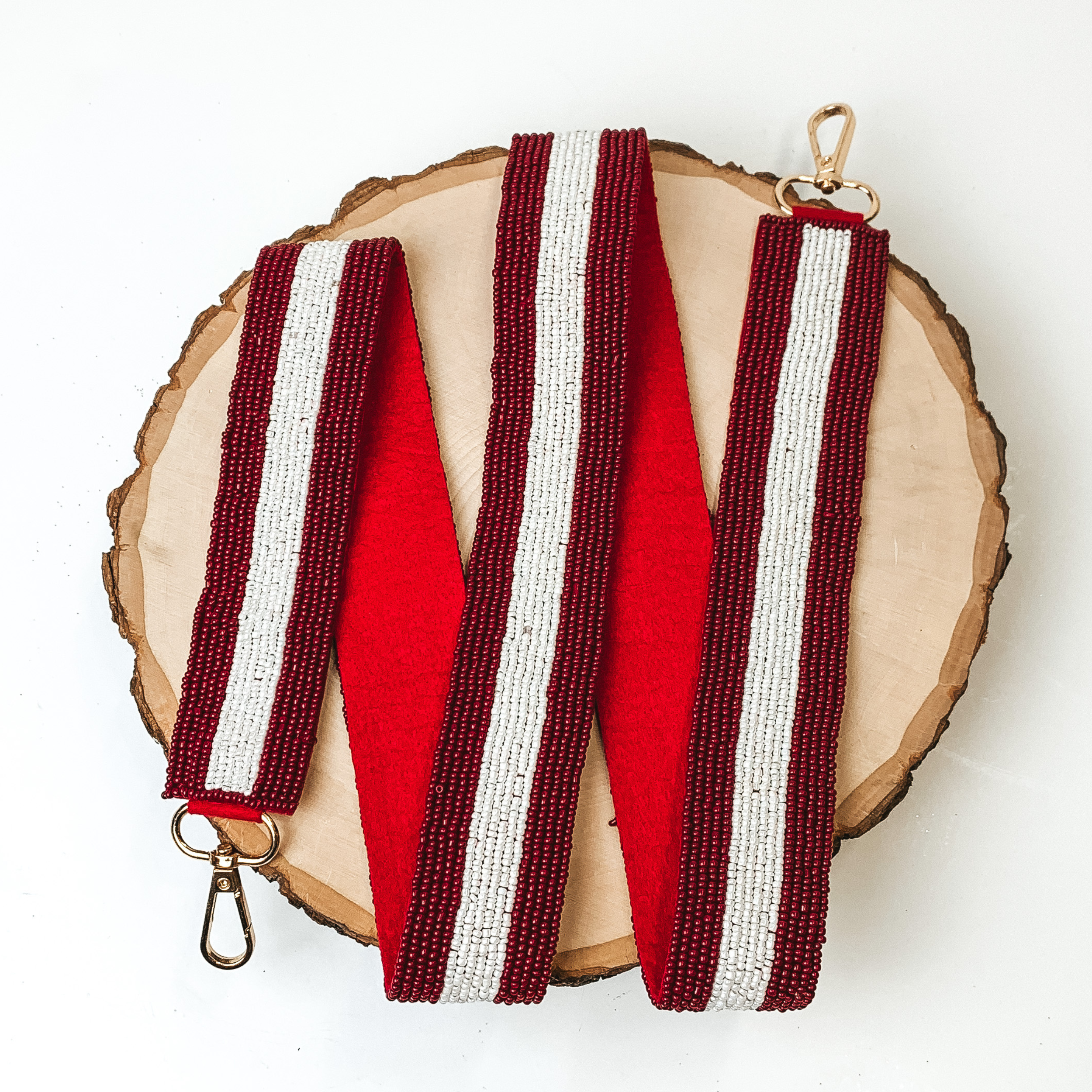 Beaded White Stripe Purse Strap in Maroon, pictured on a piece of wood, with a white background. 