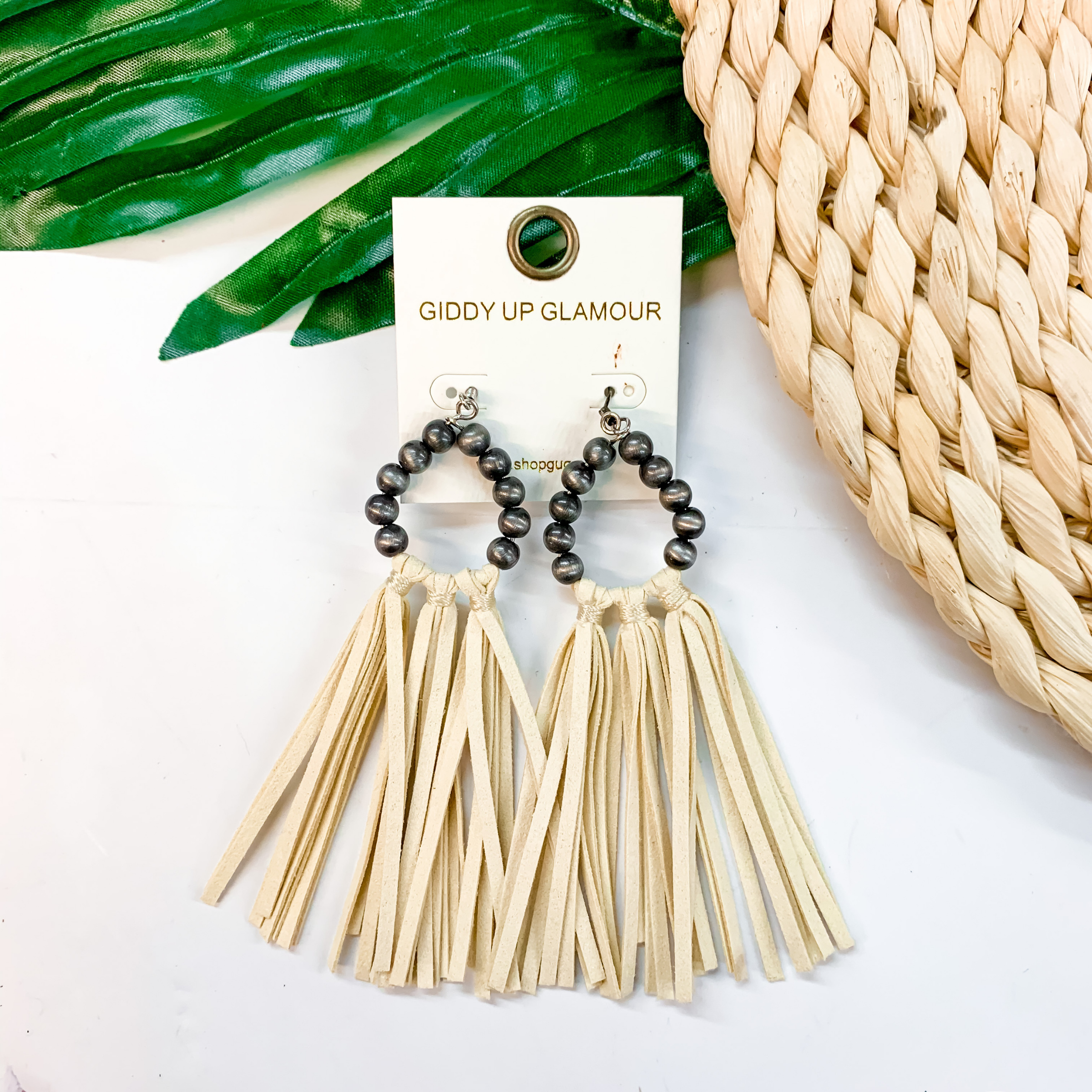Faux Navajo pearl earrings with ivory tassels. These earrings are pictured on a white background with a basket and a green palm leaf.