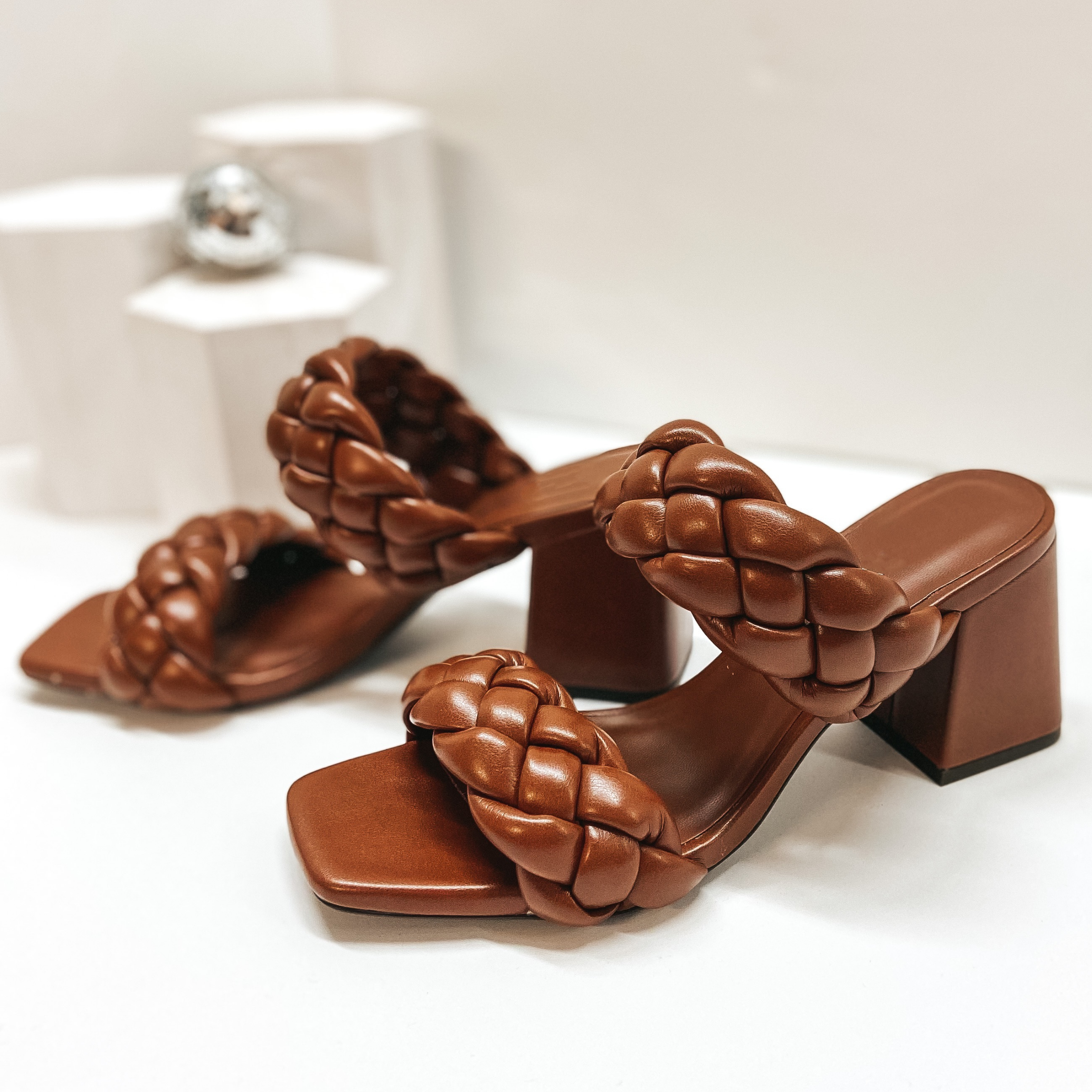 Brown braided block heels with two straps. Pictured against white background.