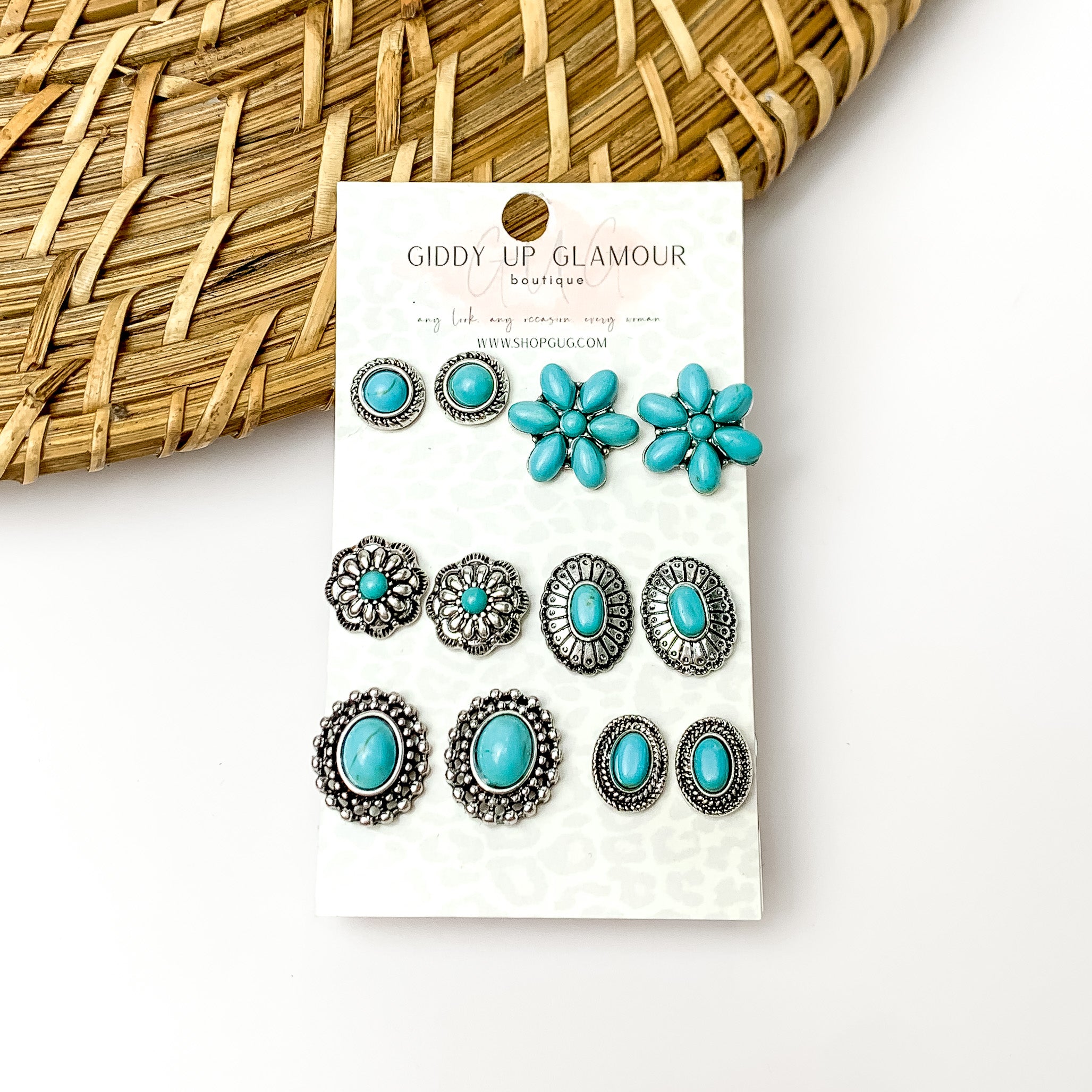 Set of six turquois and silver designed earrings. Pictured on a white background with a wood like decoration in the top left corner.