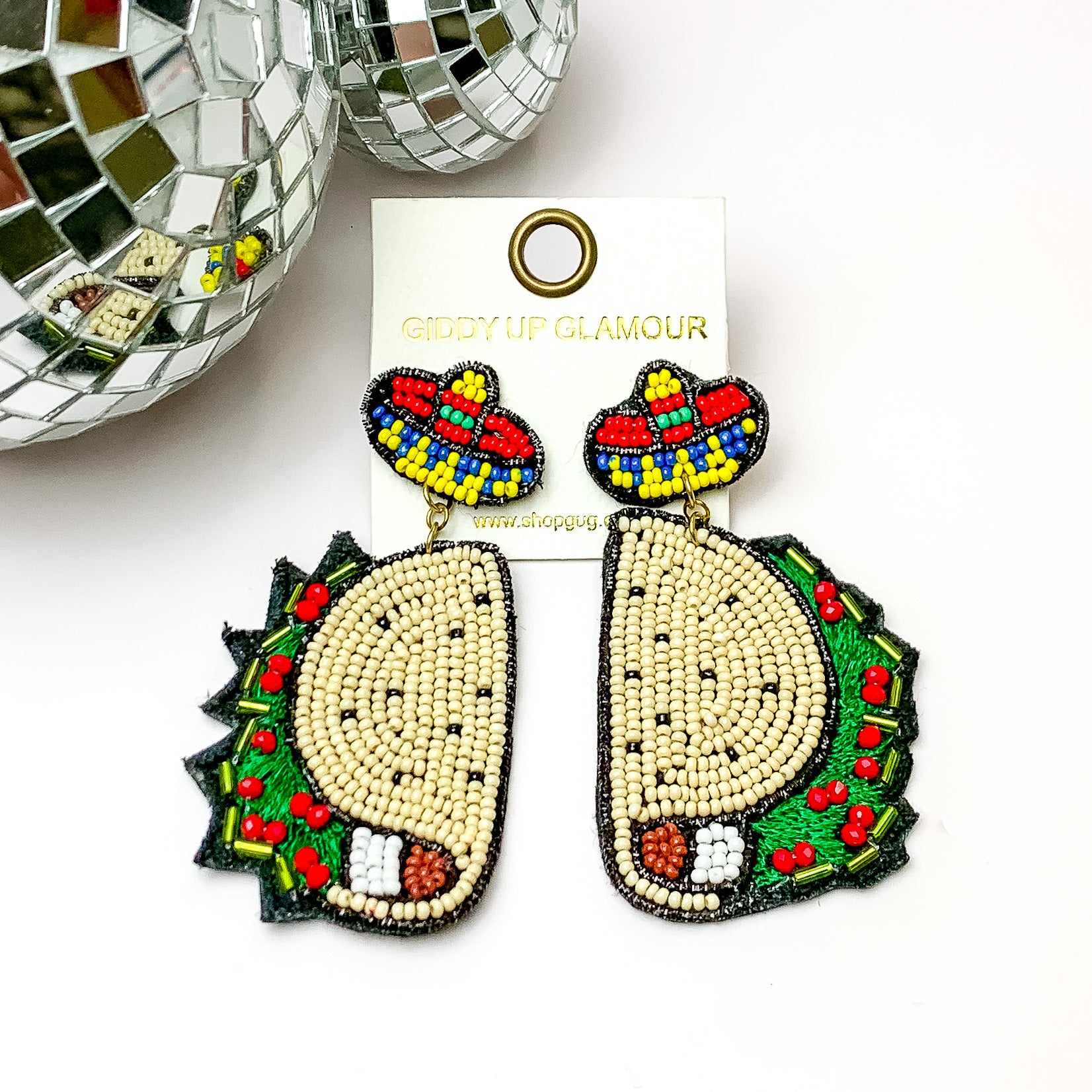 Beaded multi color festive taco earrings. Pictured on a white background with disco balls at the top left. 