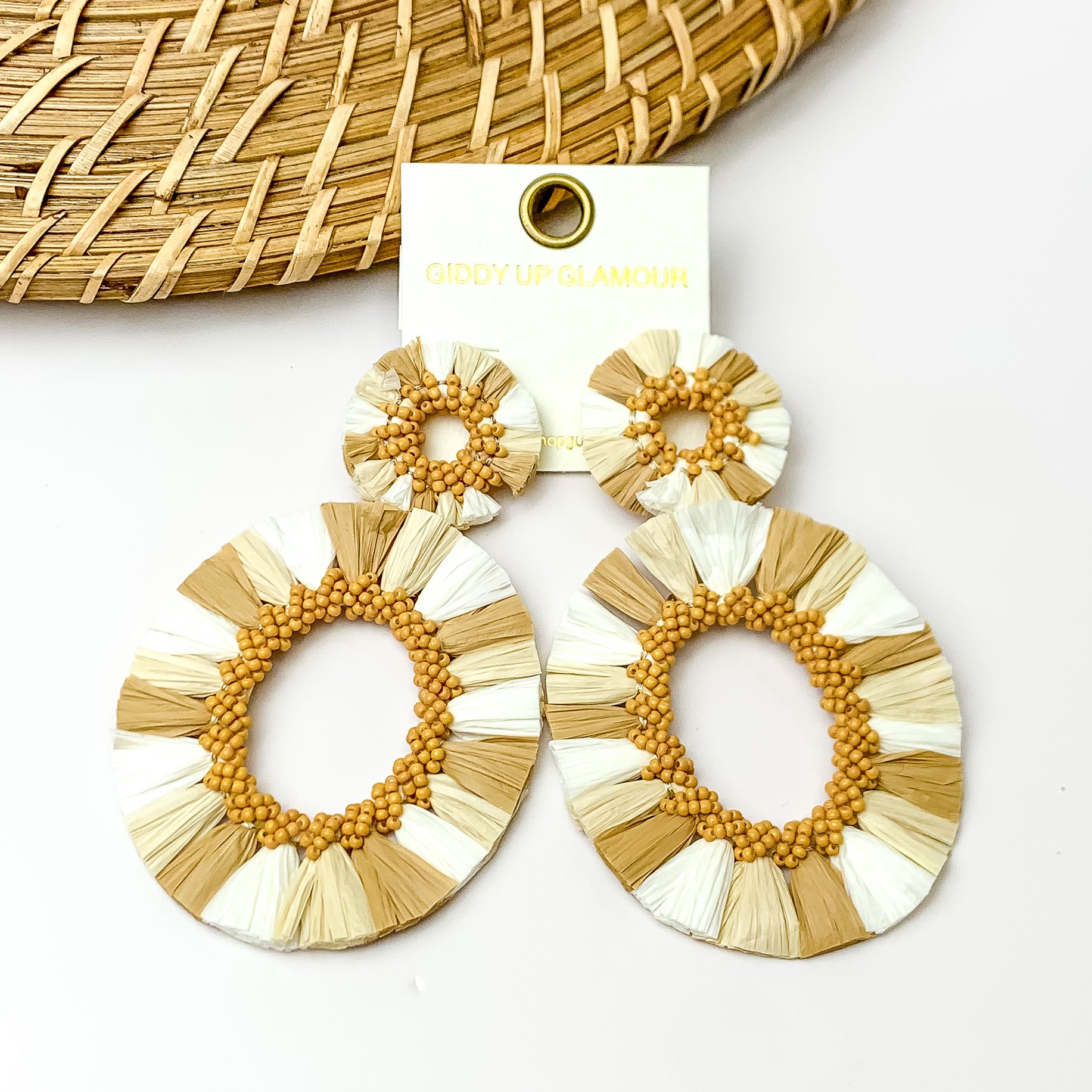White and shades of tan open hoop earrings with tan beads on the inside. Pictured with a white background and wood decorations in the top left corner.