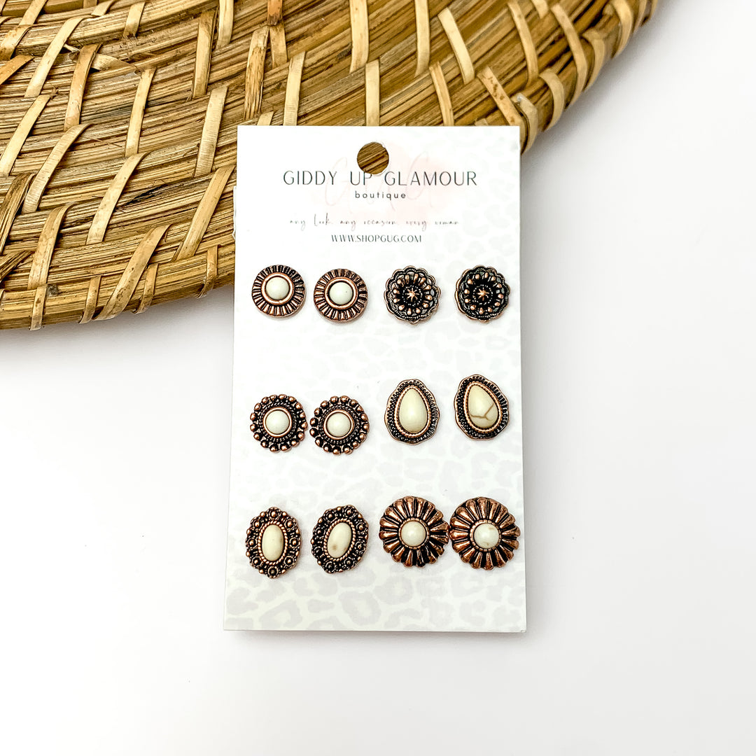 Off white and copper tone designed earrings. Pictured on a white background with a wood like decoration in the top left corner.