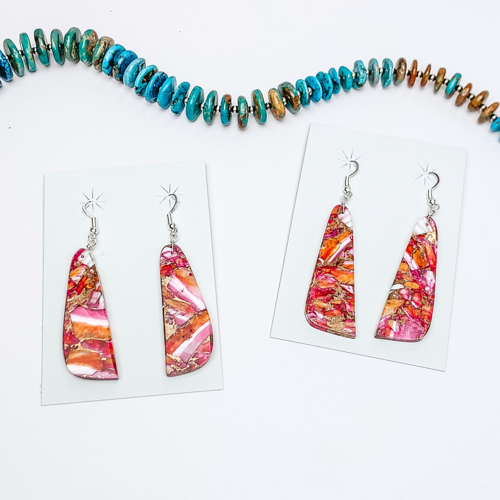 Centered in the picture is pink dhalia mix slab earrings. A turquoise necklace is set above the earrings. All on a white background.