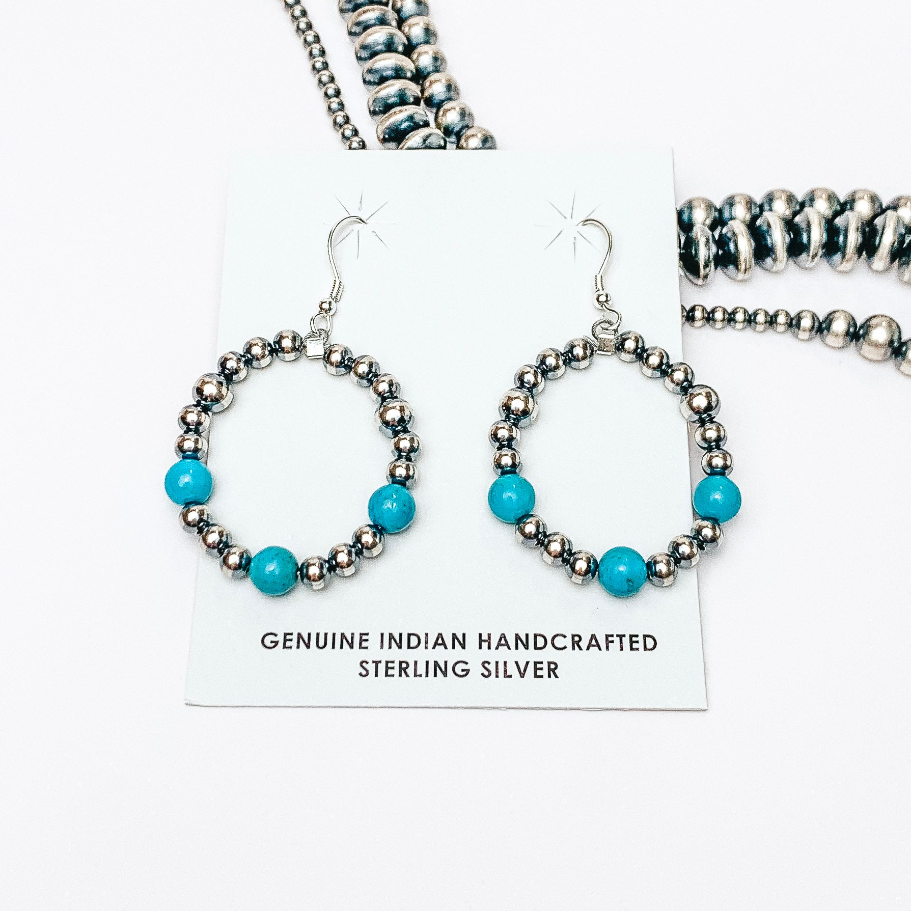Centered in the picture are navajo pearl and turquoise drop earrings. Navajo pearls are in the background. 
