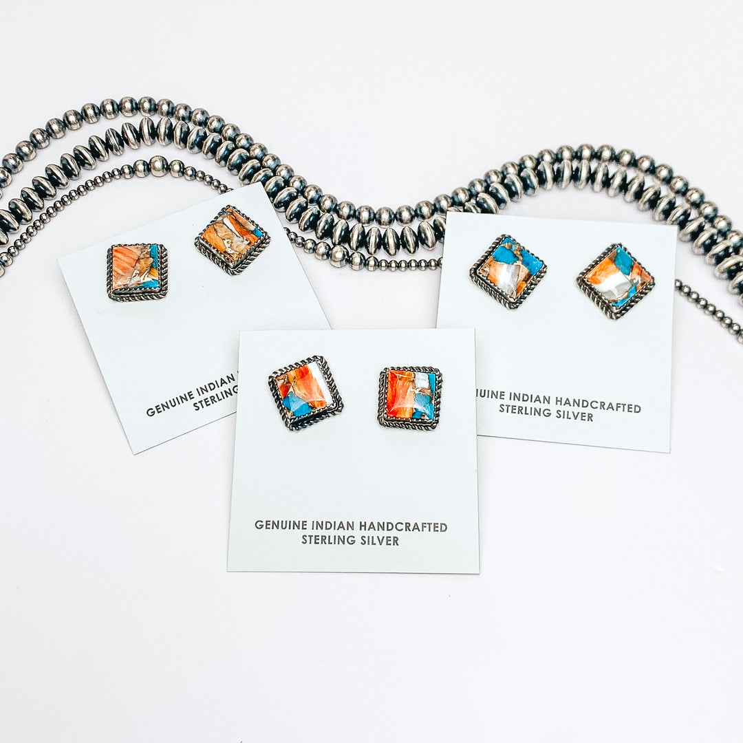 Three turquoise mix studs are in the middle of the picture, on a white background. Navajo pearls are laid above the studs. 